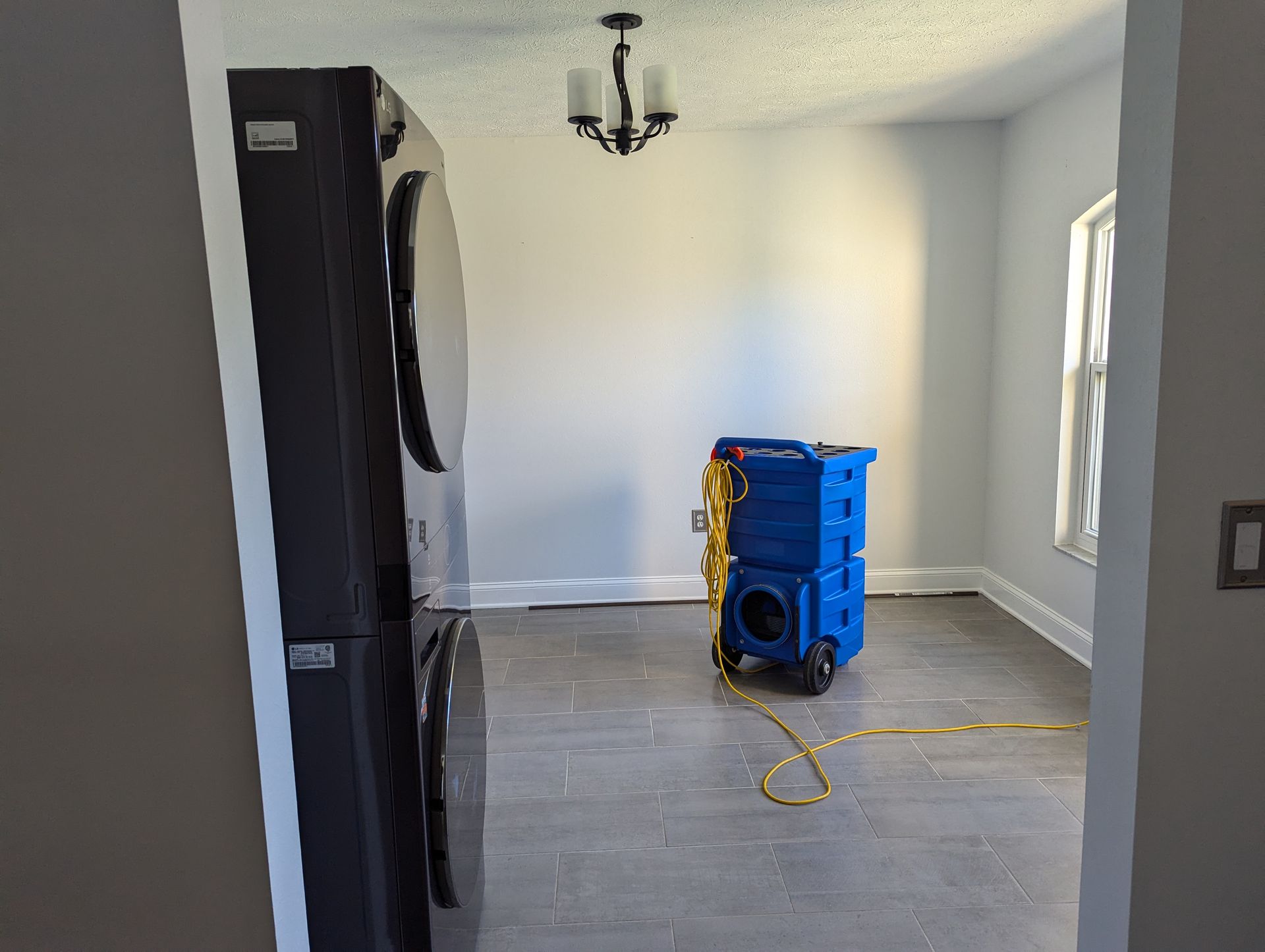 A room with a washer and dryer in it and a blue machine in the middle of the room.