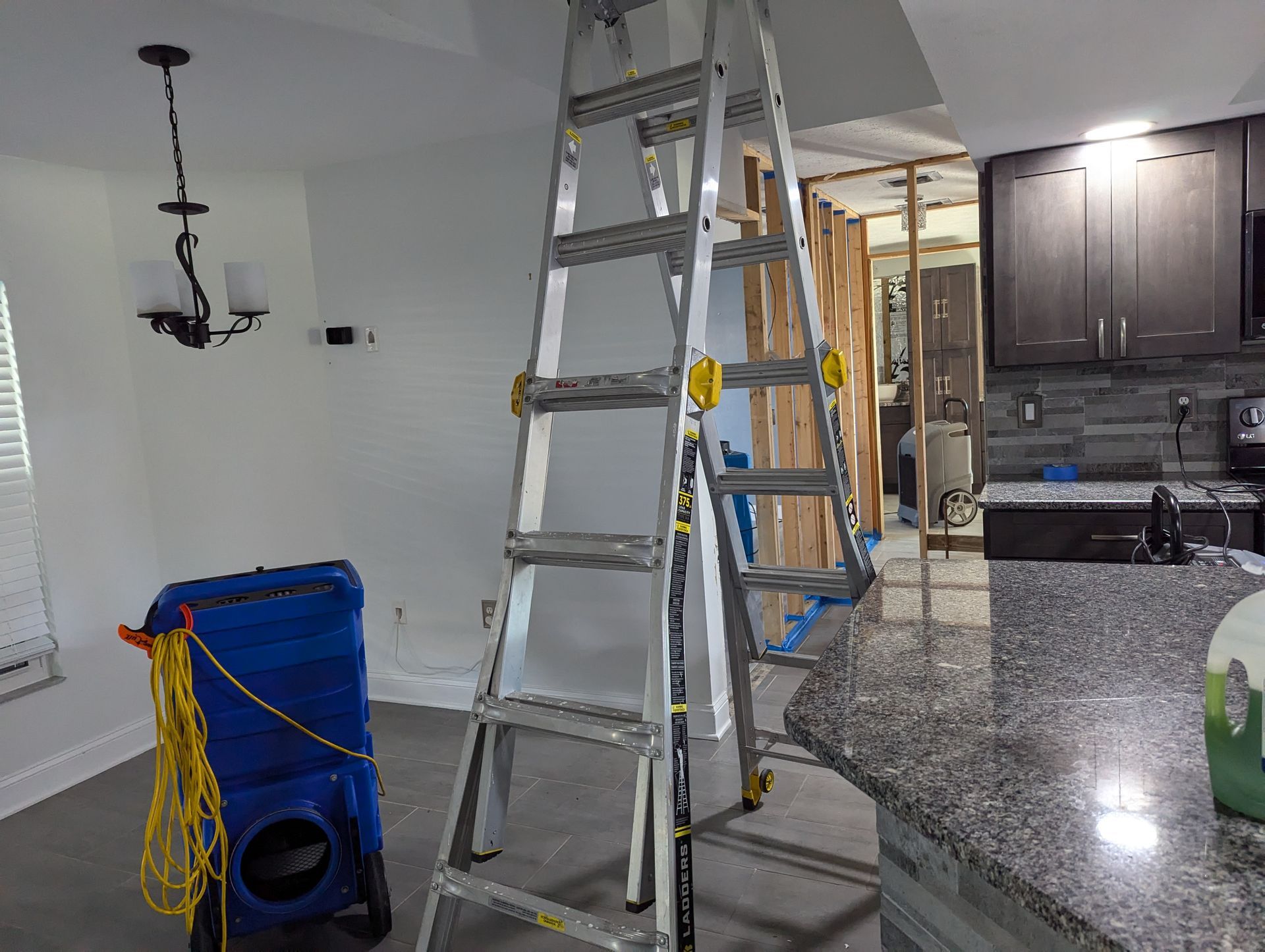 A ladder is sitting in the middle of a kitchen.