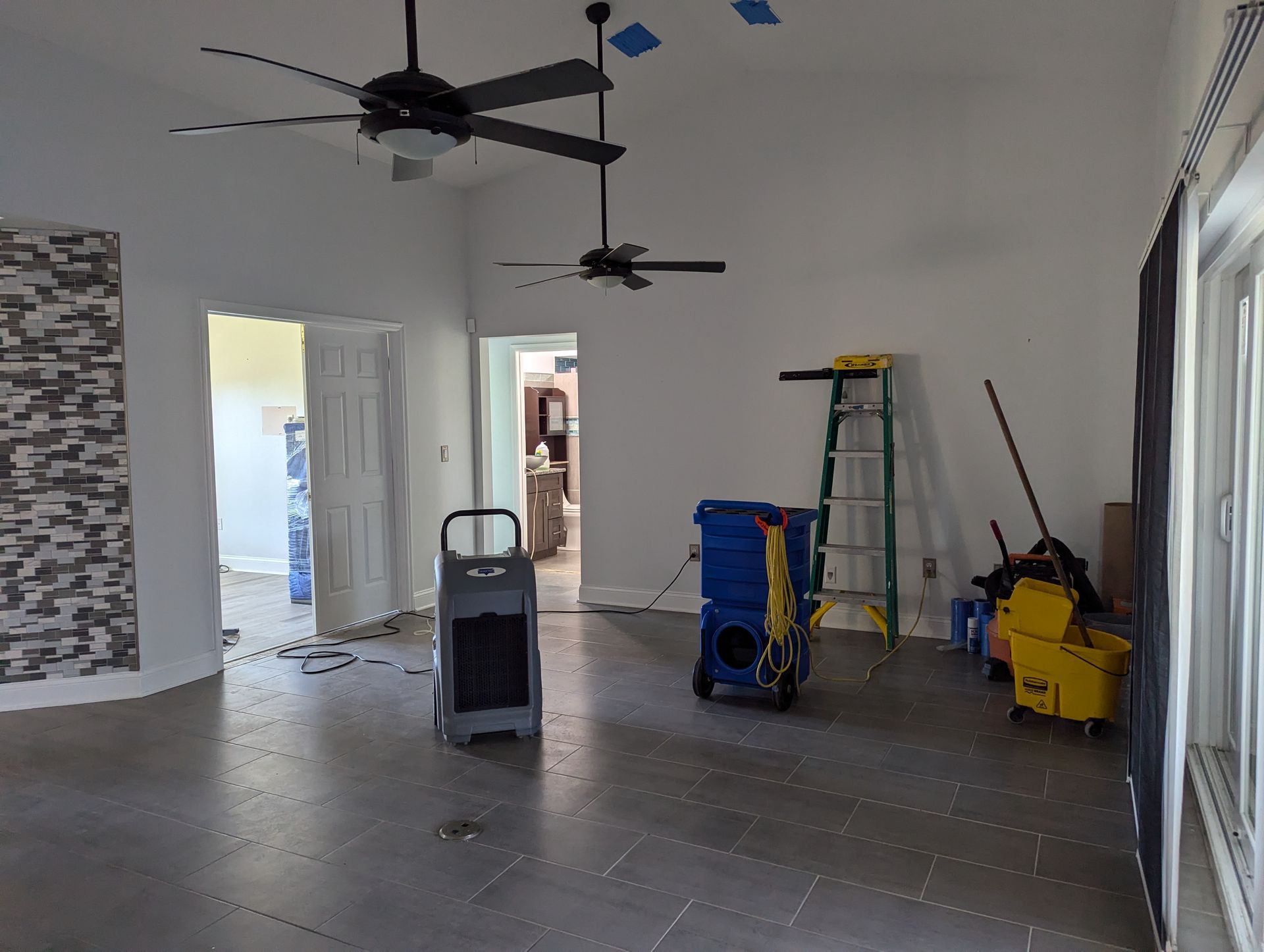 An empty room with a ceiling fan and a mop