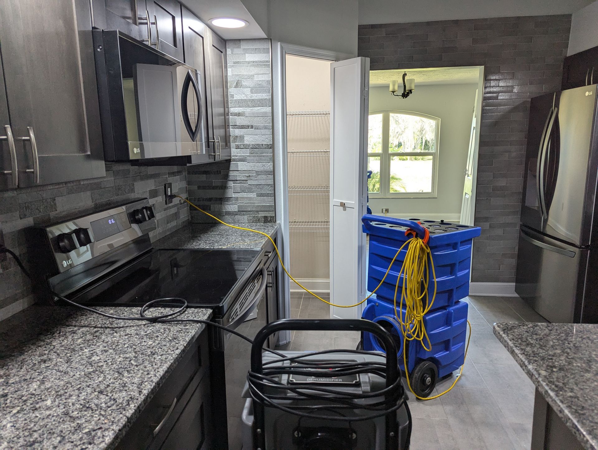A kitchen with a stove , refrigerator , microwave and a vacuum cleaner.