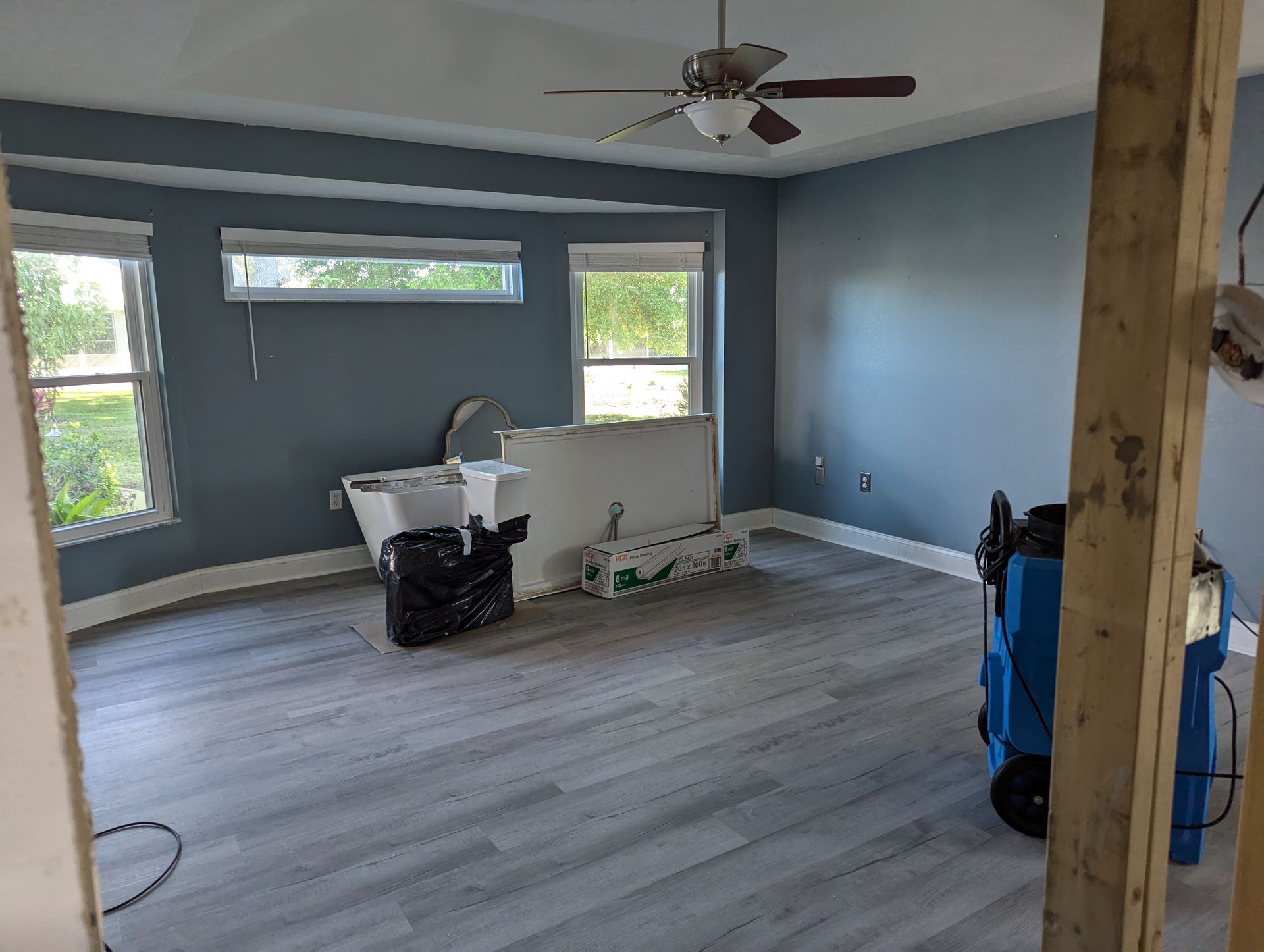 An empty room with a ceiling fan and a window.