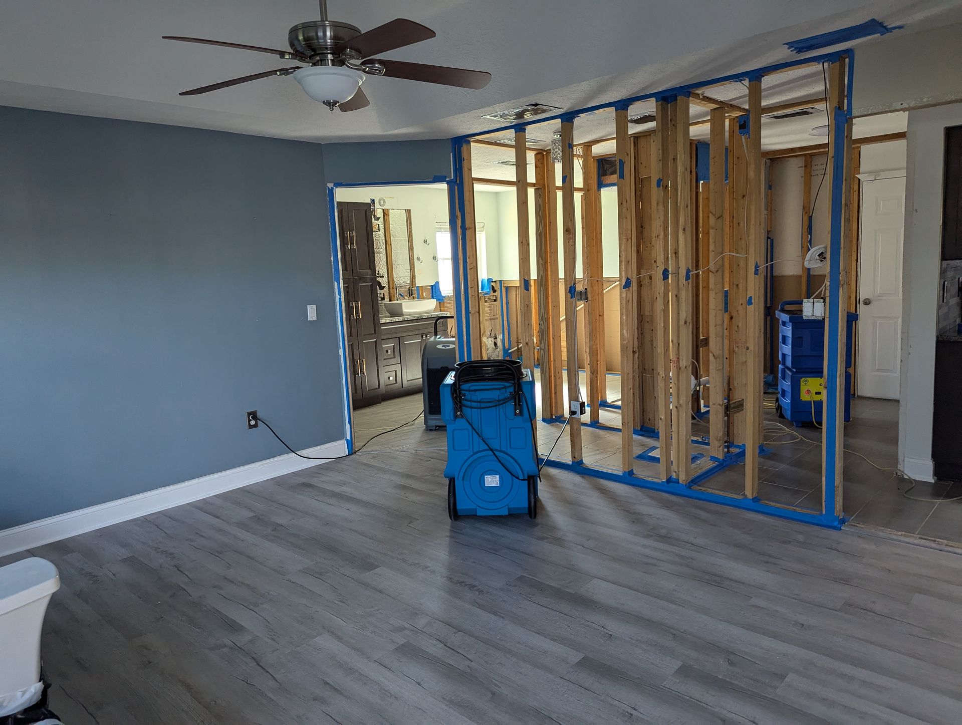 A living room with a ceiling fan and a blue bag in it.