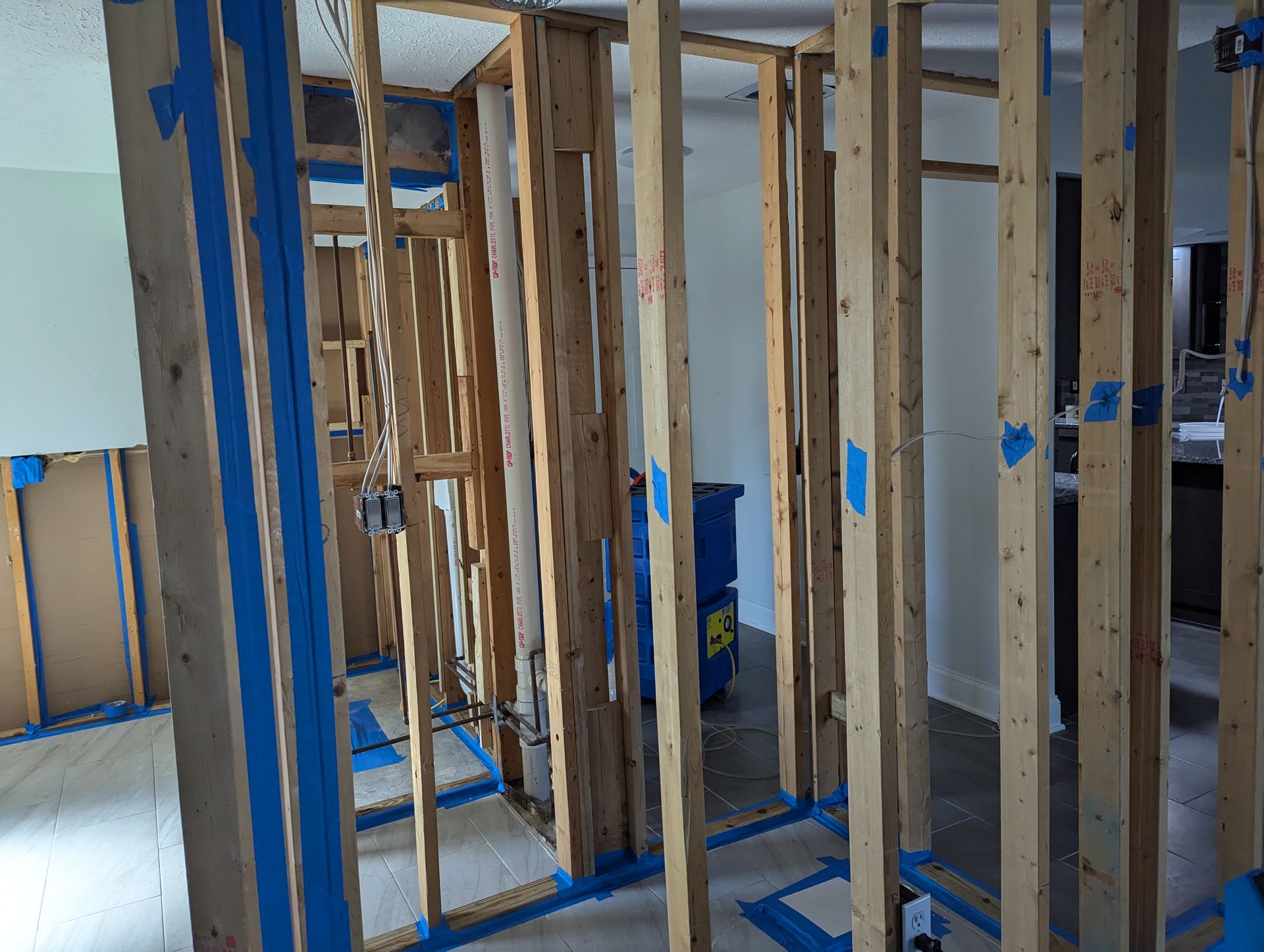 A room with wooden beams and blue tape on the walls.