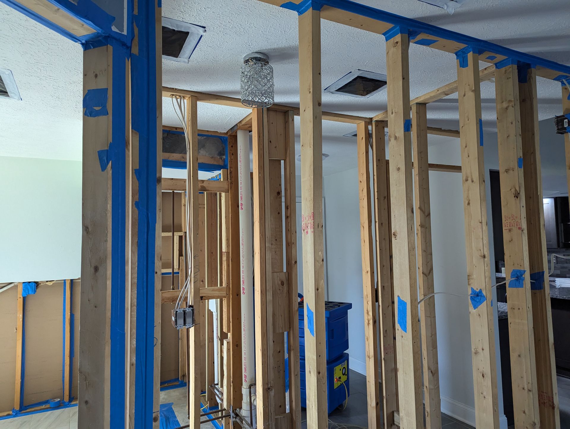 A room with a lot of wooden beams and blue tape on the walls.