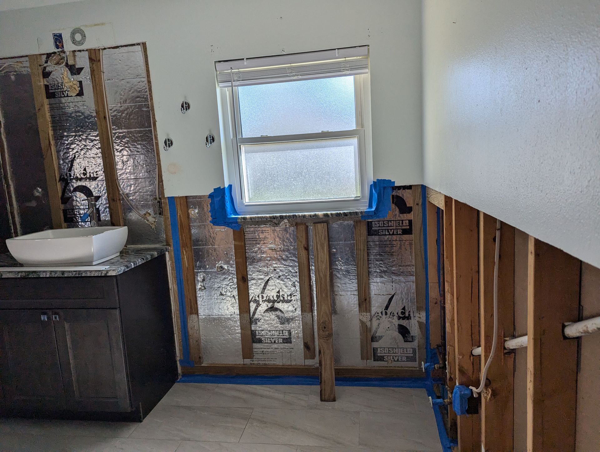 A bathroom under construction with a sink and a window.