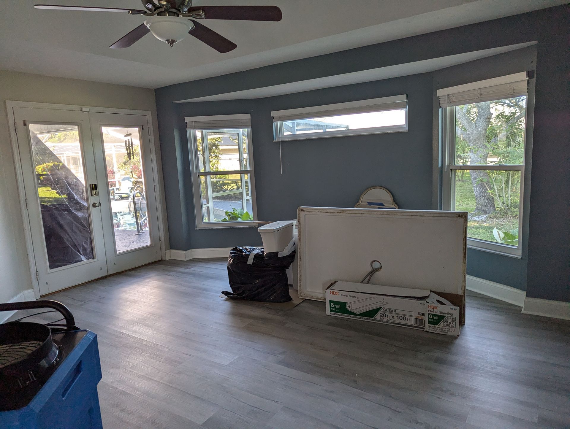 A living room with a ceiling fan and a lot of windows.