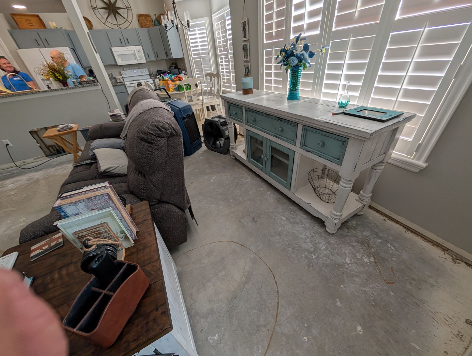Living room with a gray sofa, white console table, and shuttered windows.