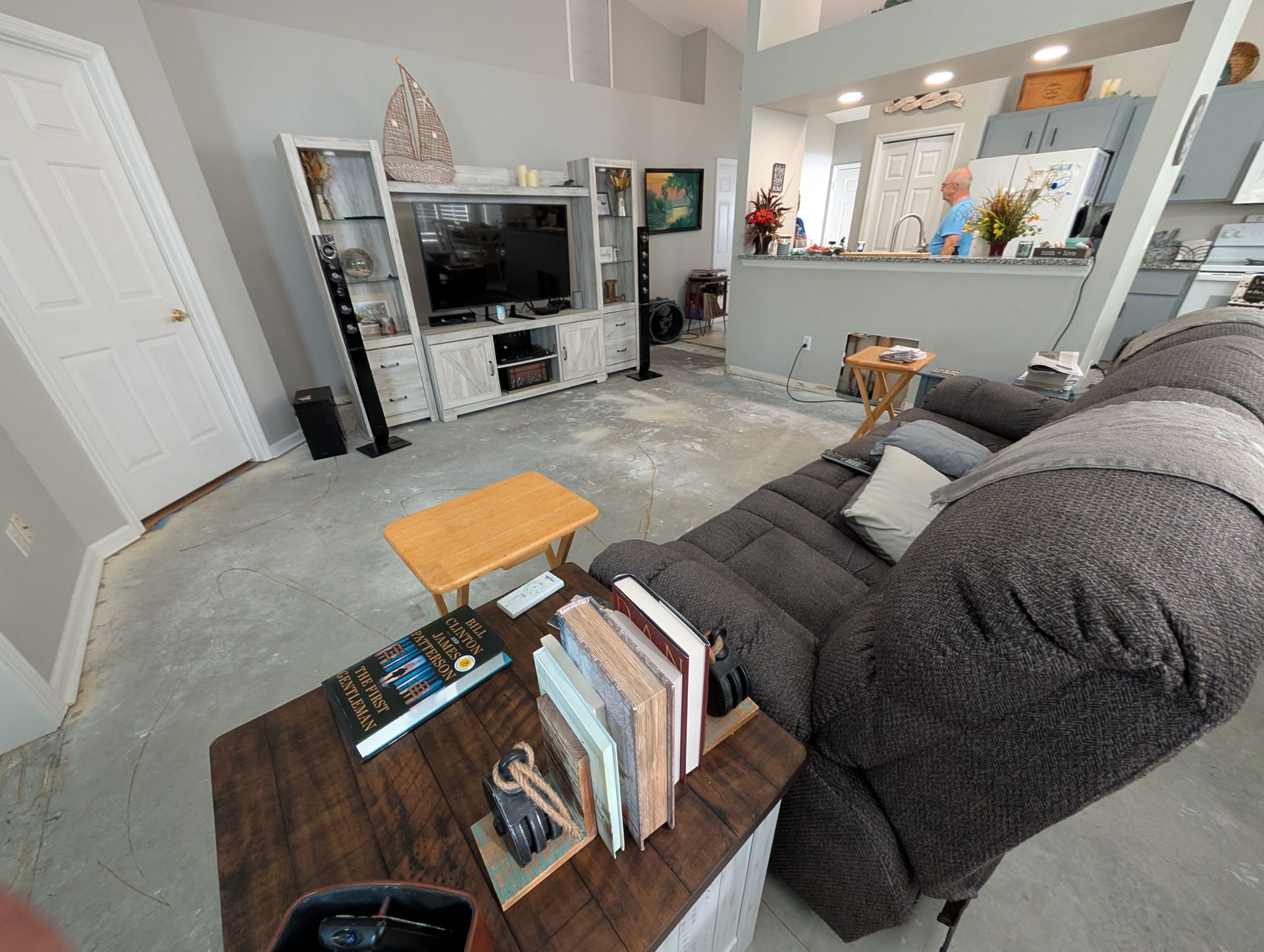 Living room with TV, recliner, and small table. A person is visible in the background.