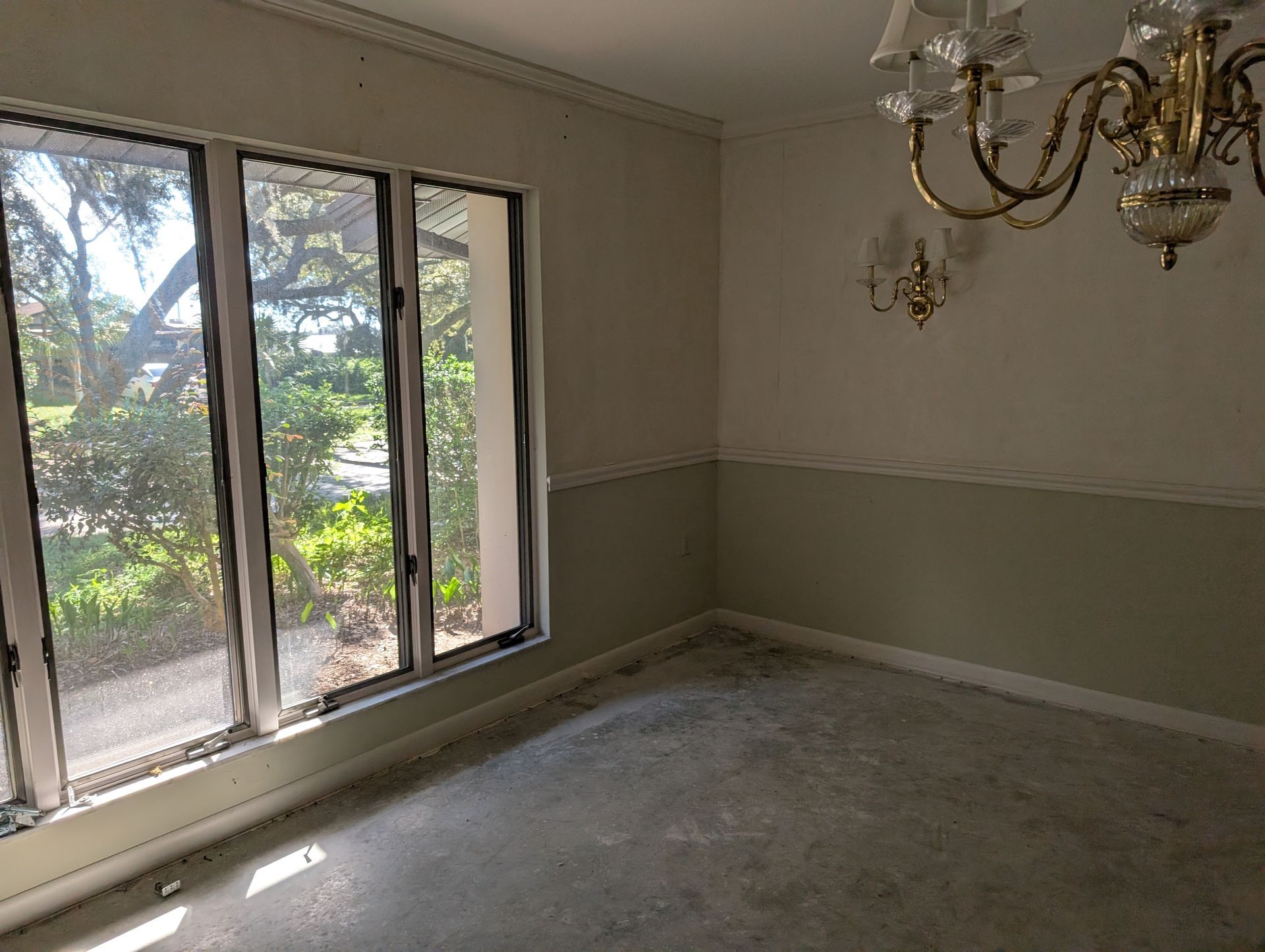 Empty room with large window, two-tone walls, and chandelier.