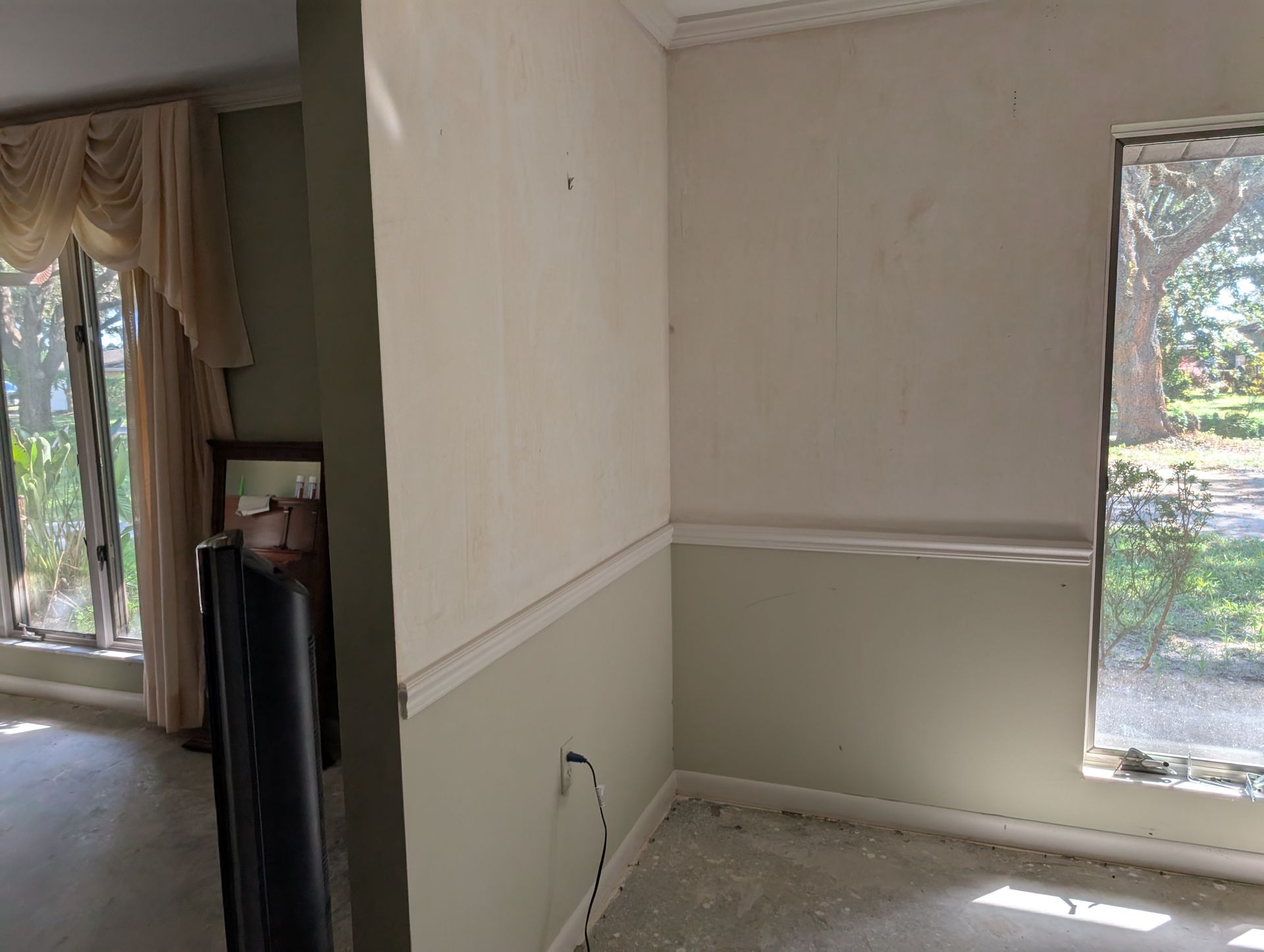 Corner of a room with light green and beige walls, window, and molding.