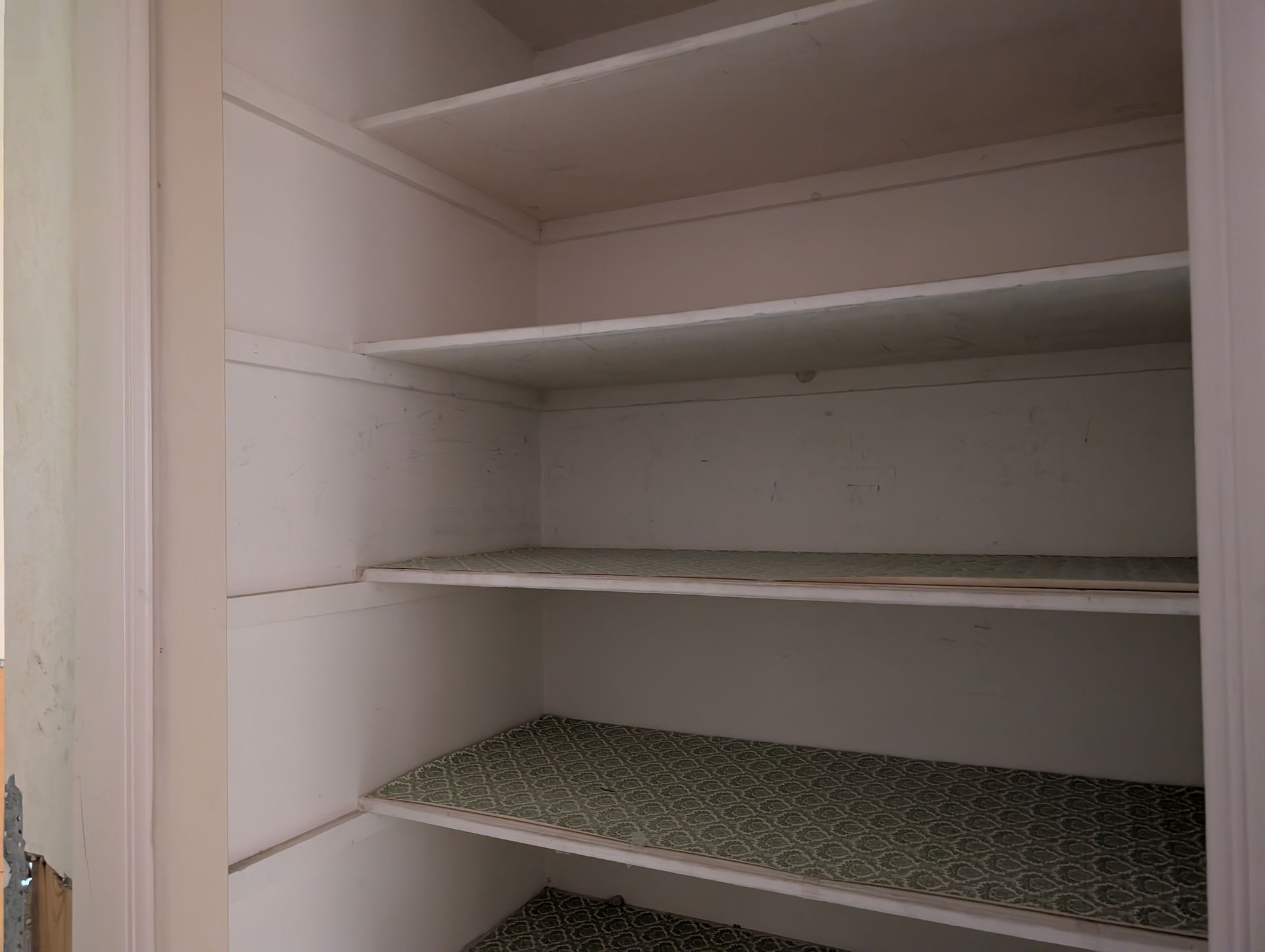 Empty white closet with four shelves, some with patterned shelf liners.