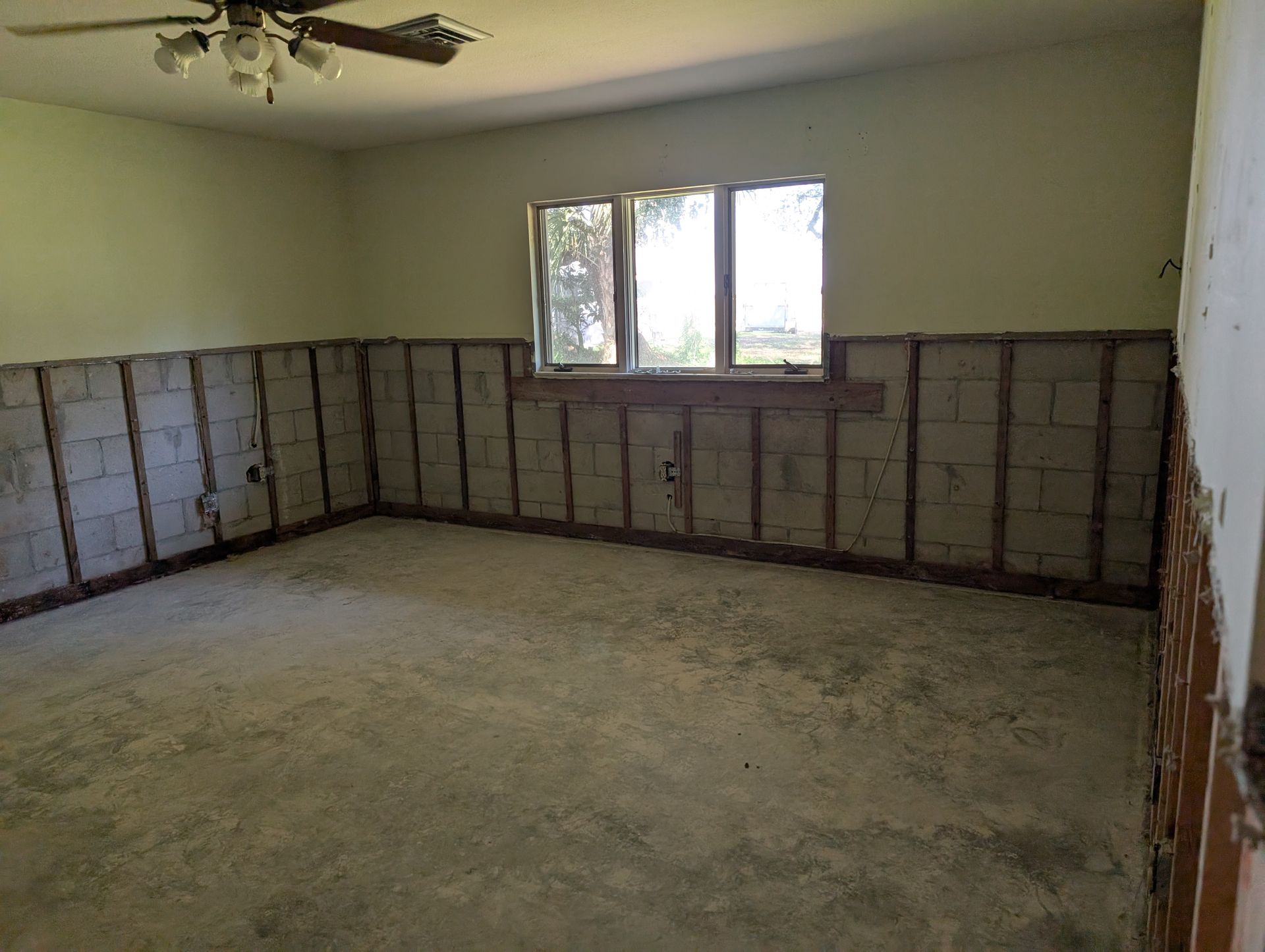 Empty room with exposed concrete block walls and window.