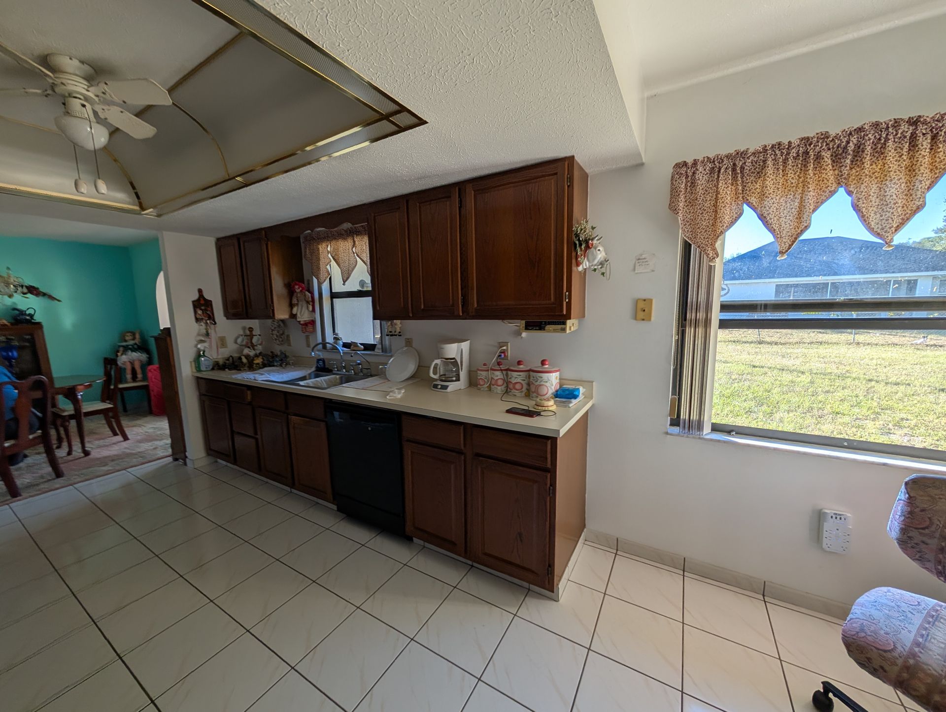 Kitchen with brown cabinets, white countertops, and a window overlooking a grassy area.
