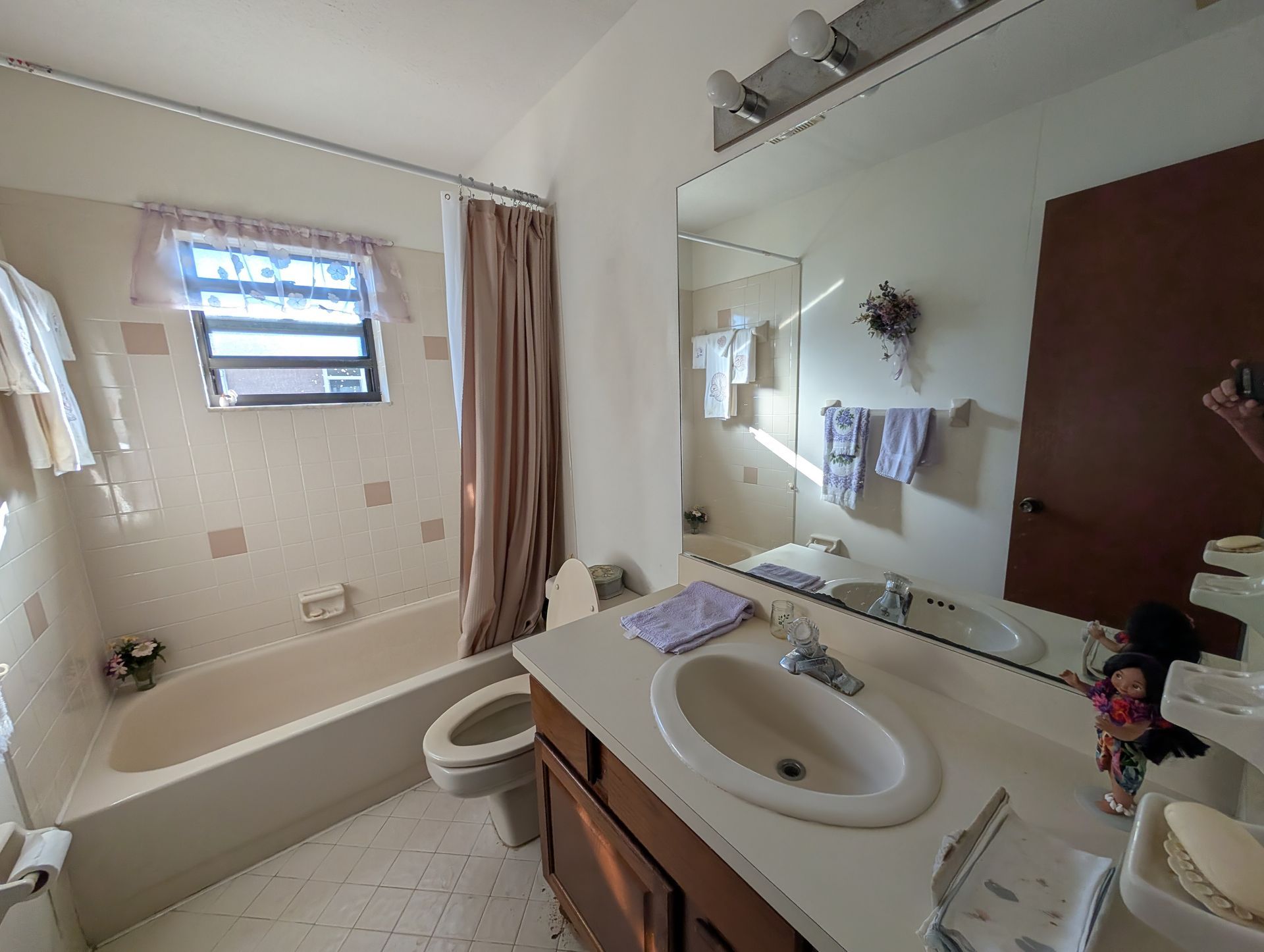 Bathroom with tub, sink, toilet, mirror, and beige walls.