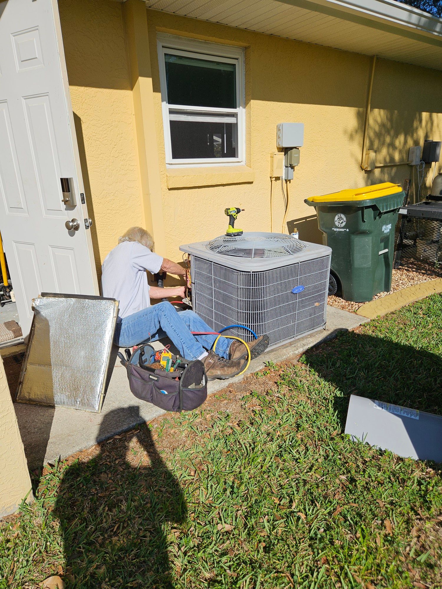 A man is working on an air conditioner outside of a house.
