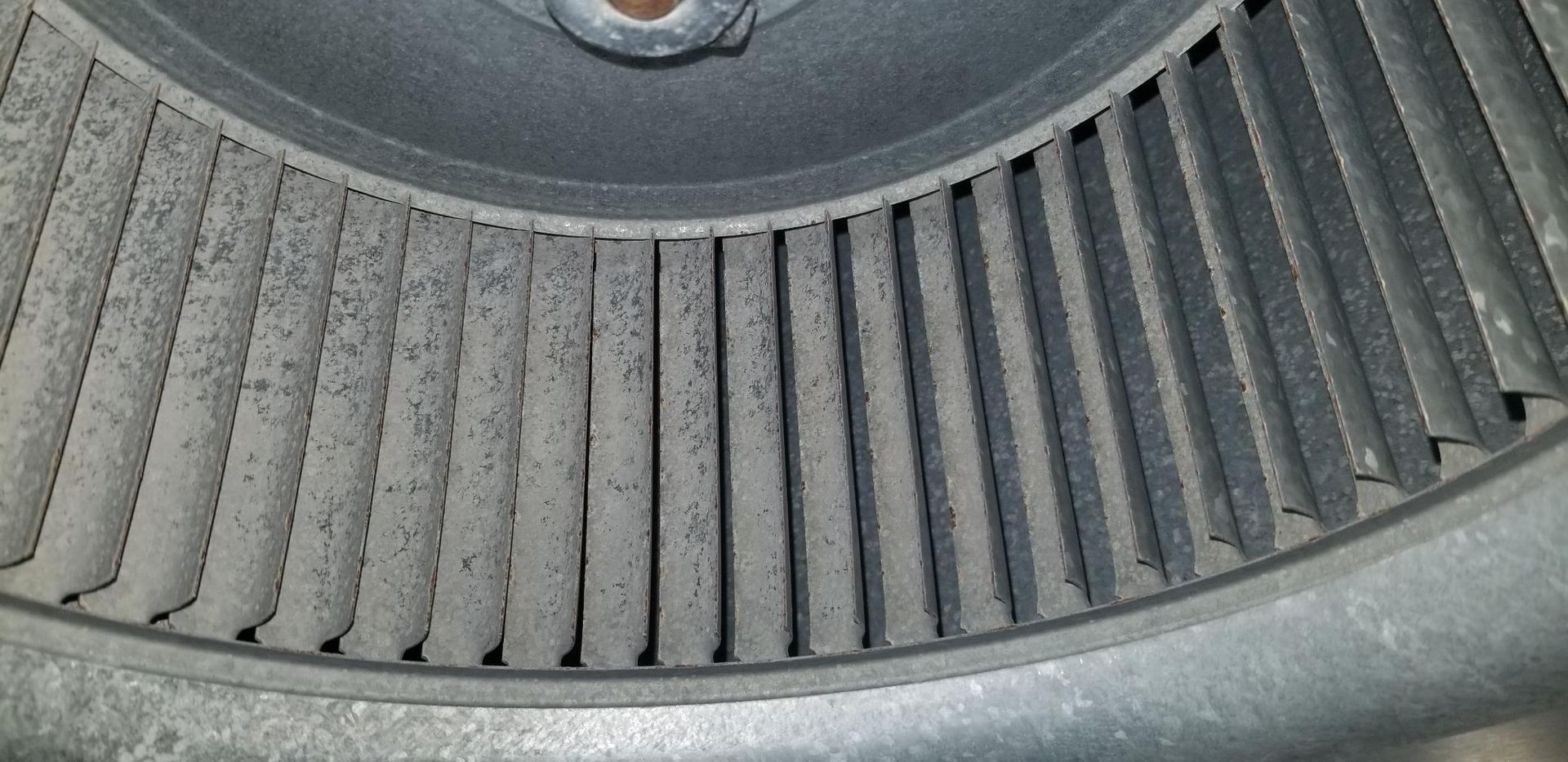A close up of a dirty air conditioner fan with a lot of dust on it.