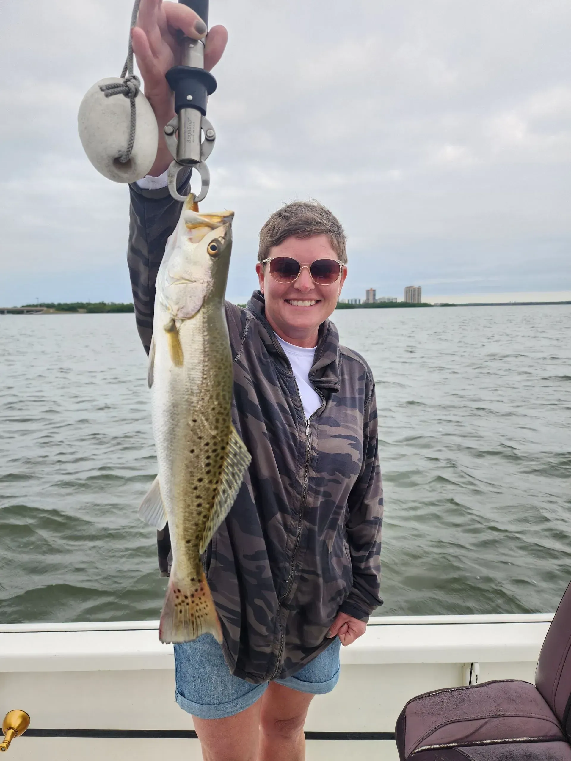 A woman is holding a fish on a boat in the water.