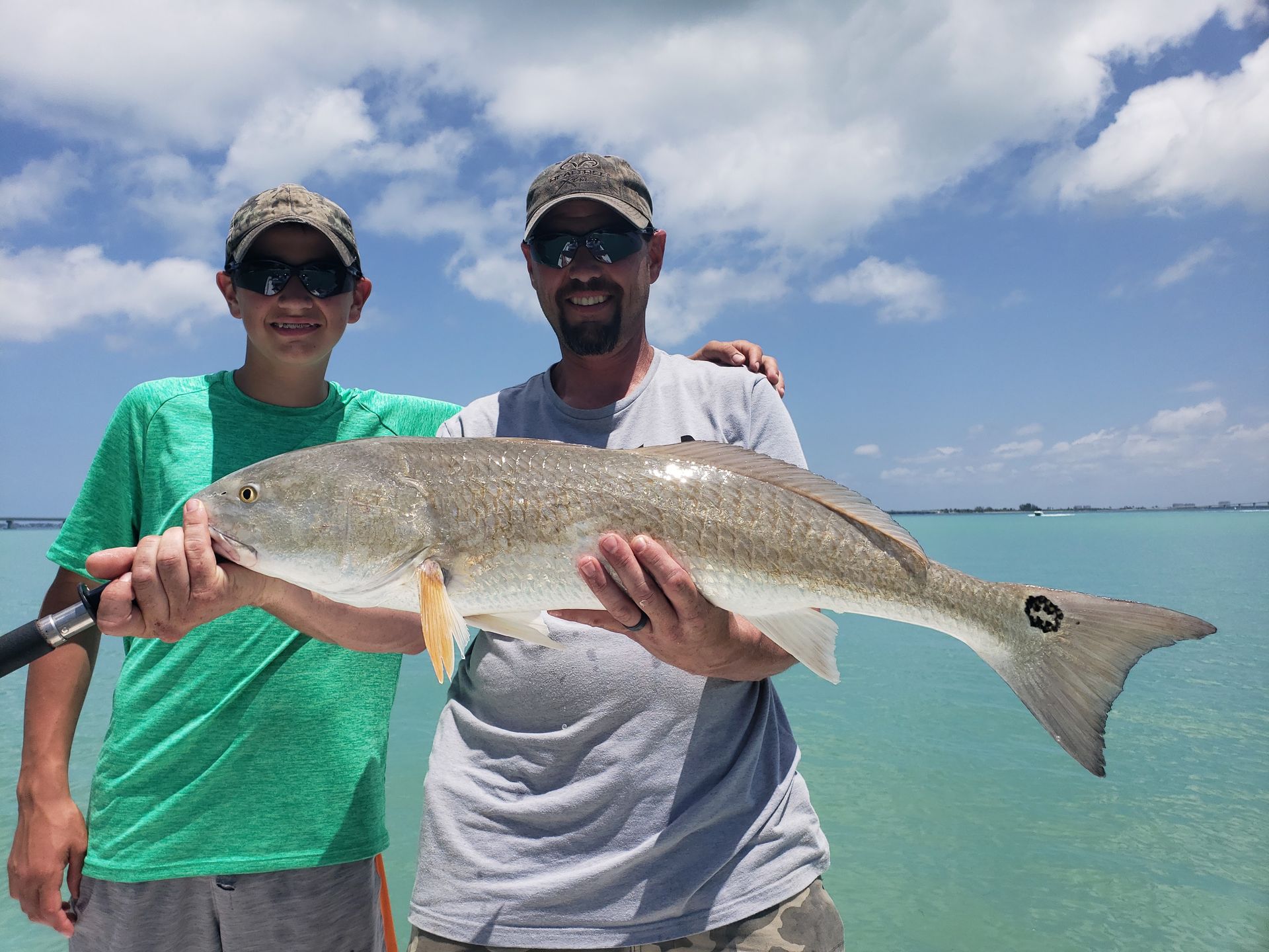 A man and a boy are holding a large fish in their hands.