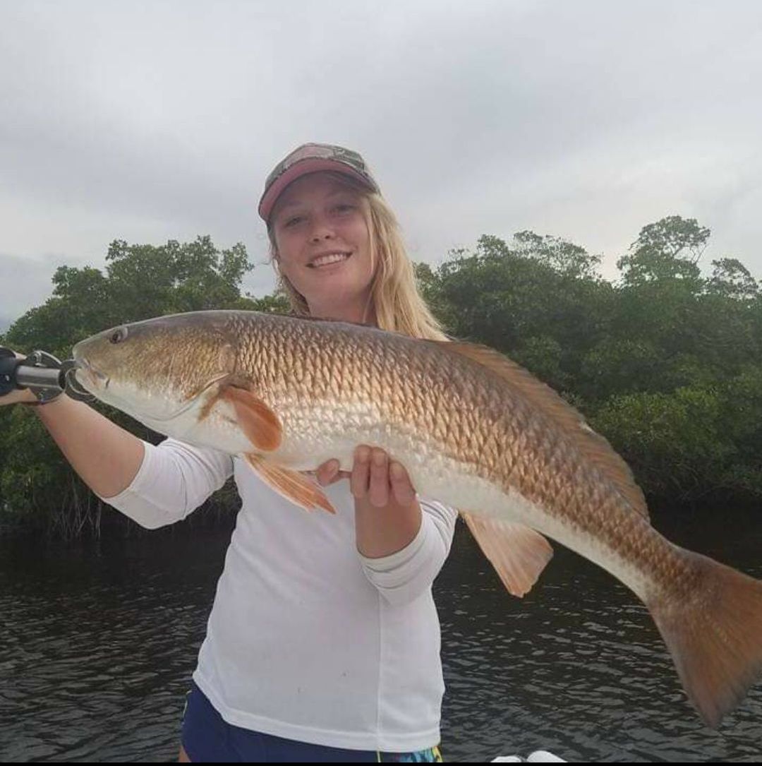 A woman is holding a large fish in her hands