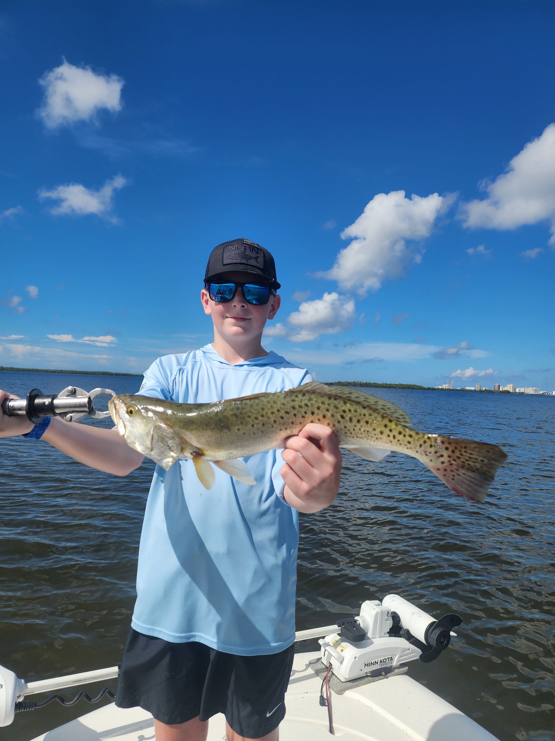 A young man is holding a large fish on a boat.