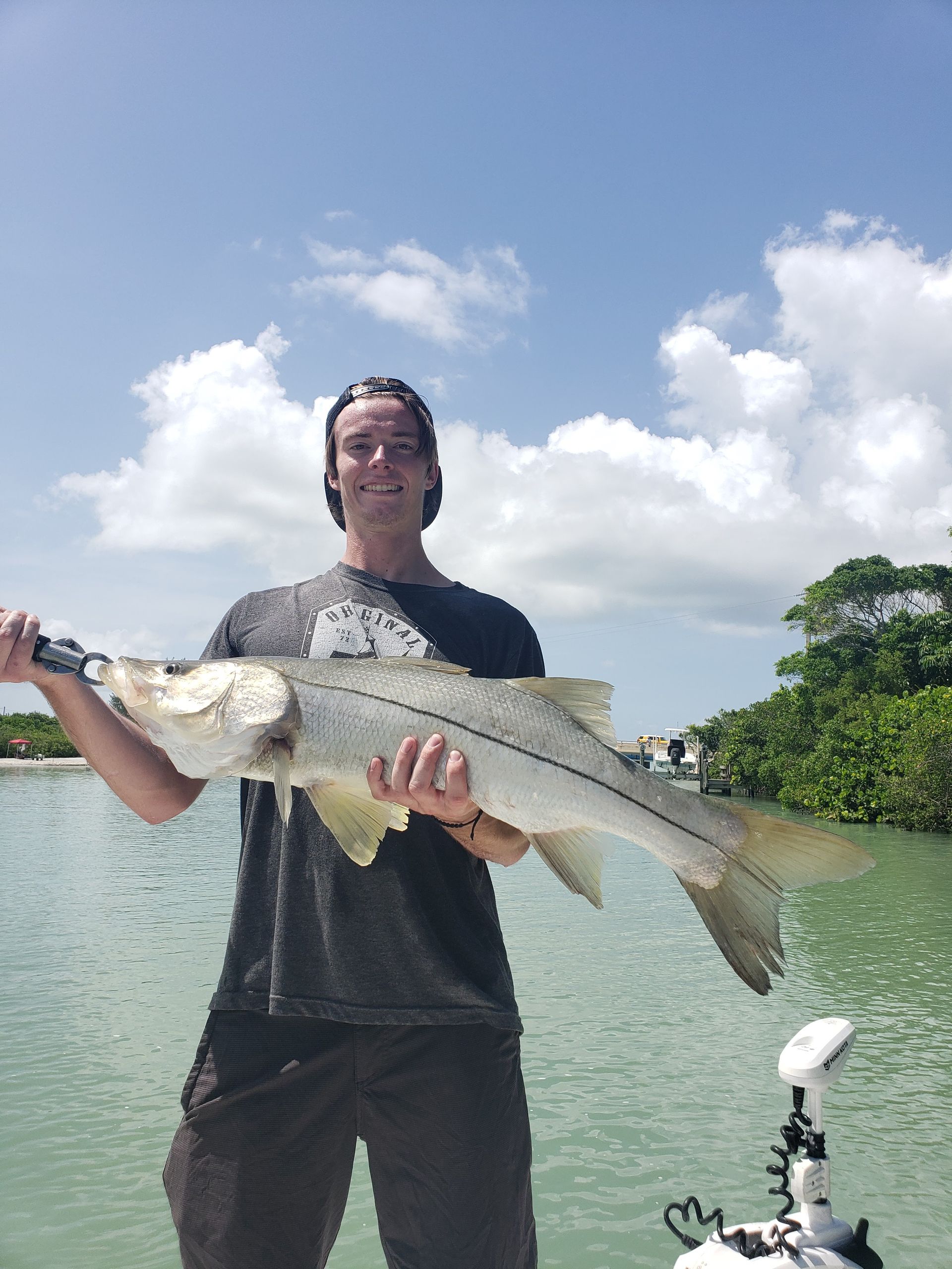A man is standing on a boat holding a large fish.