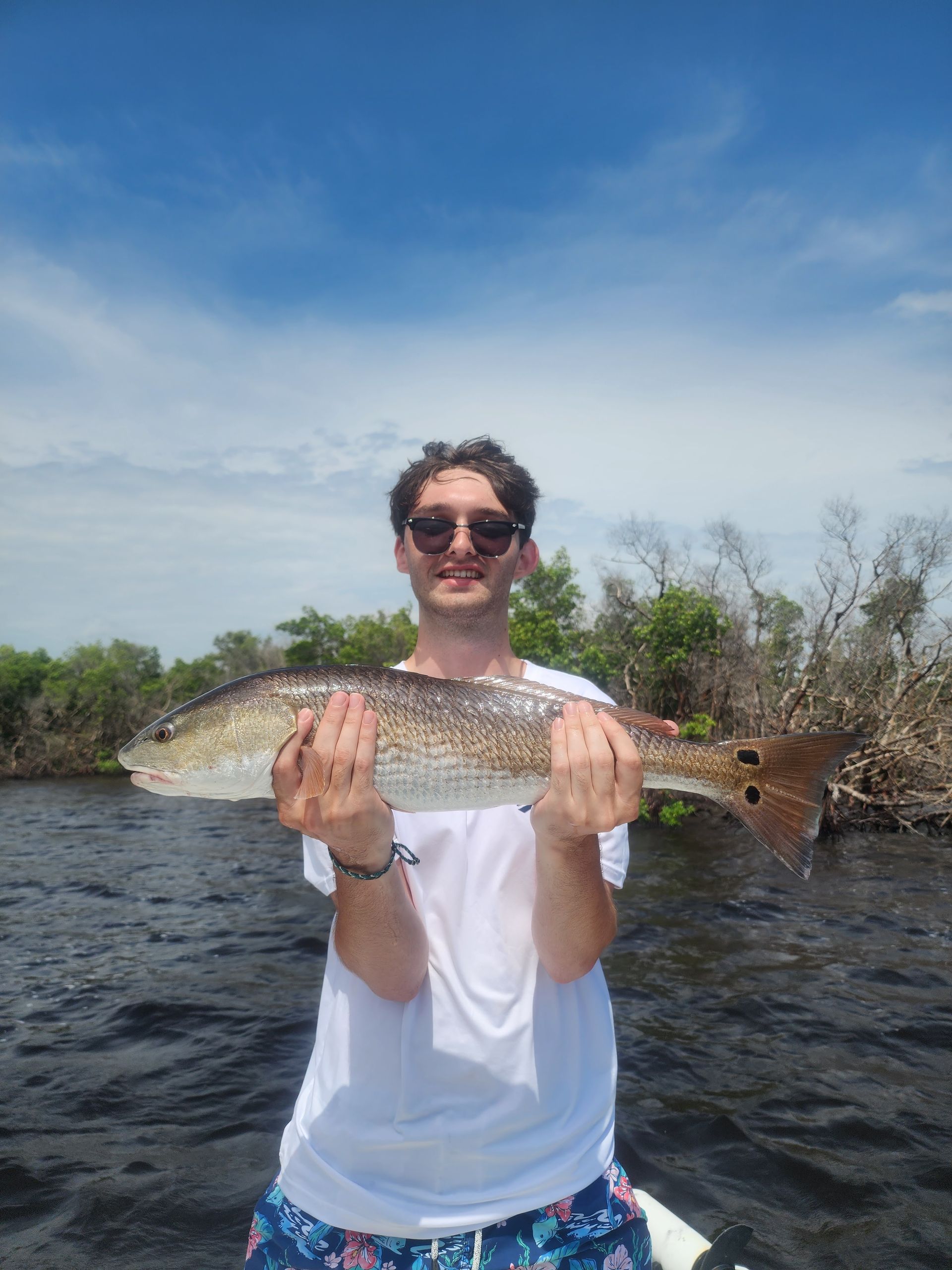 A man is holding a large fish in his hands on a boat.