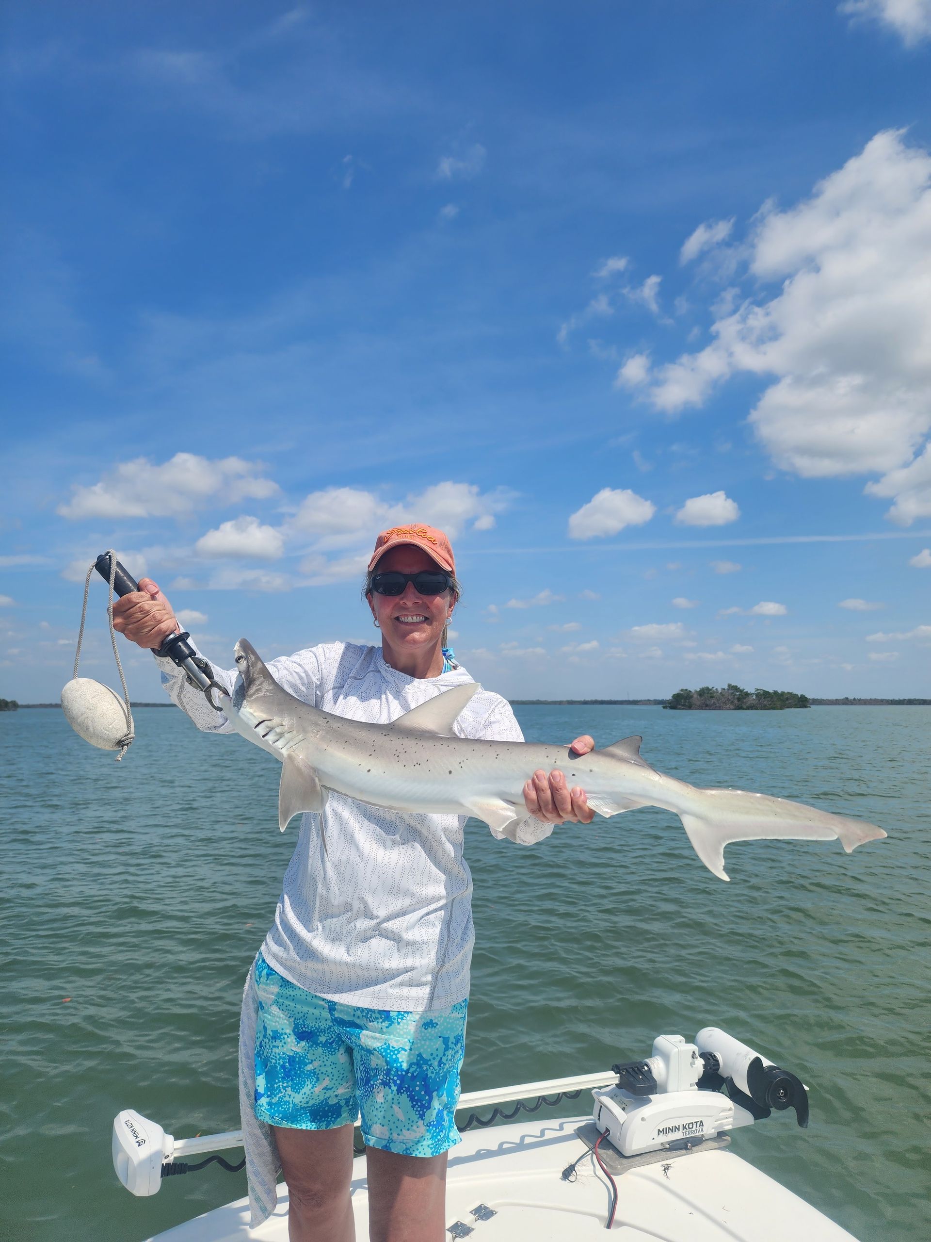 A man is holding a shark on a boat in the water.