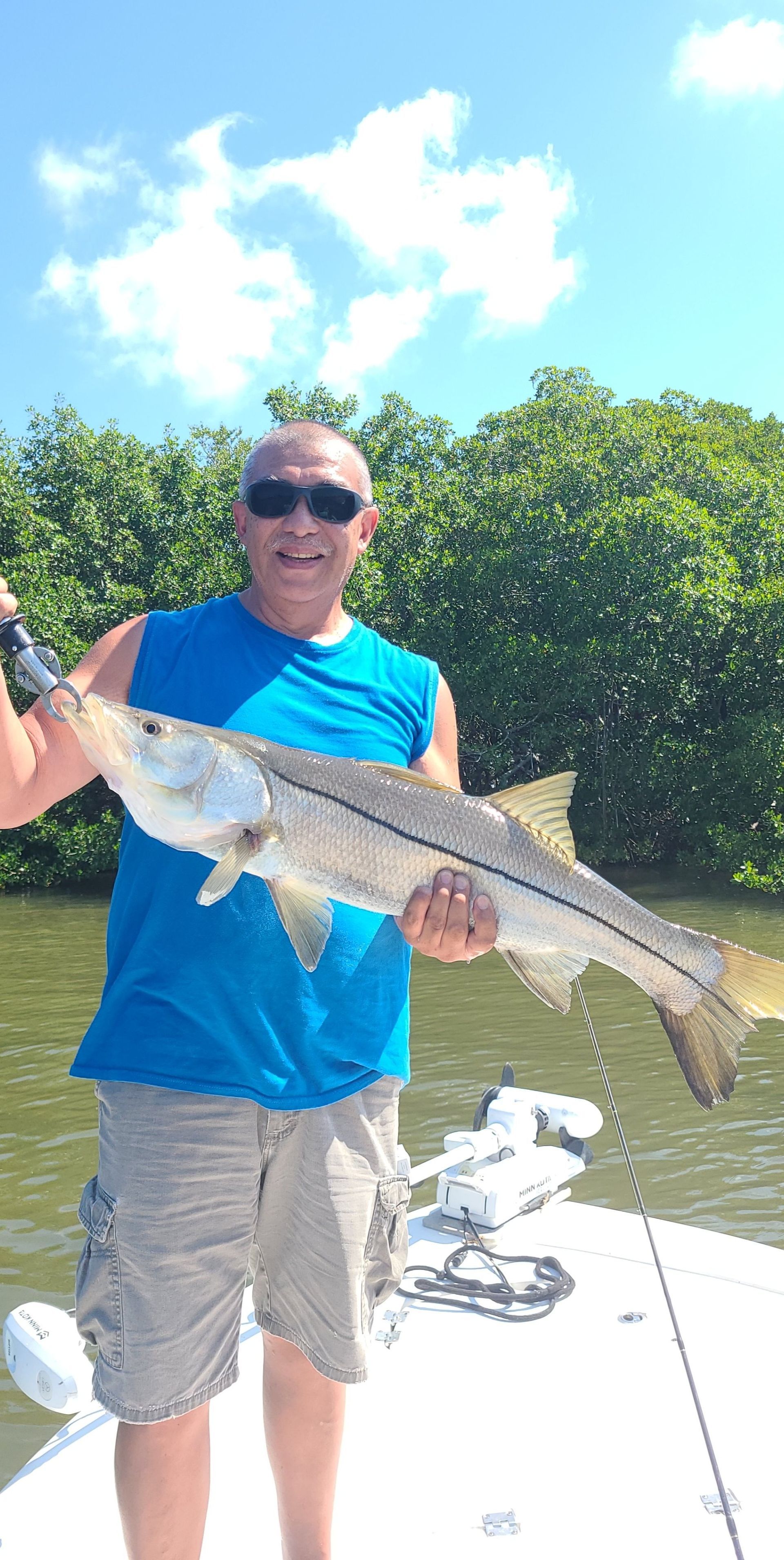 A man is standing on a boat holding a large fish.