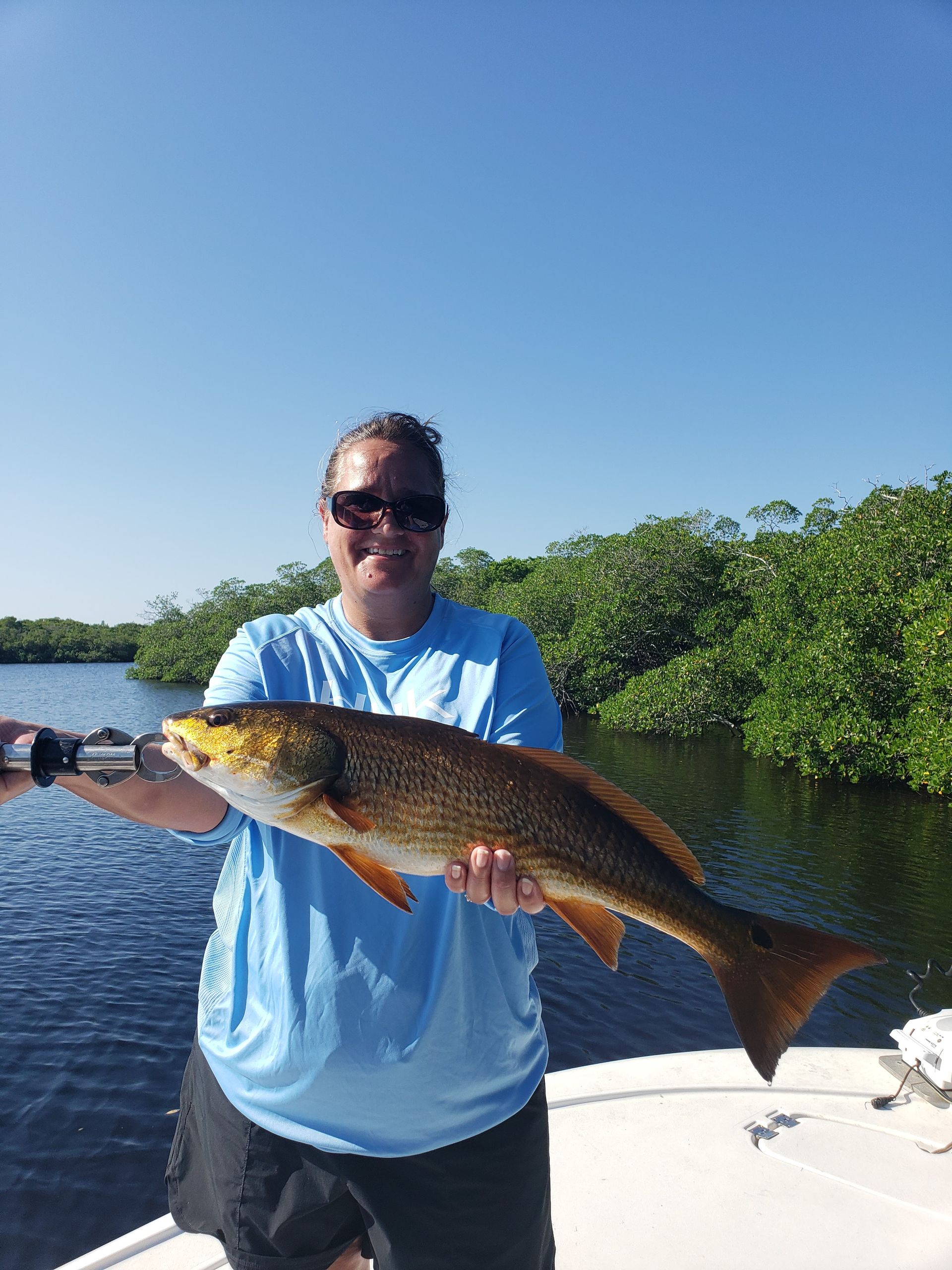 A man is holding a large fish on a boat.