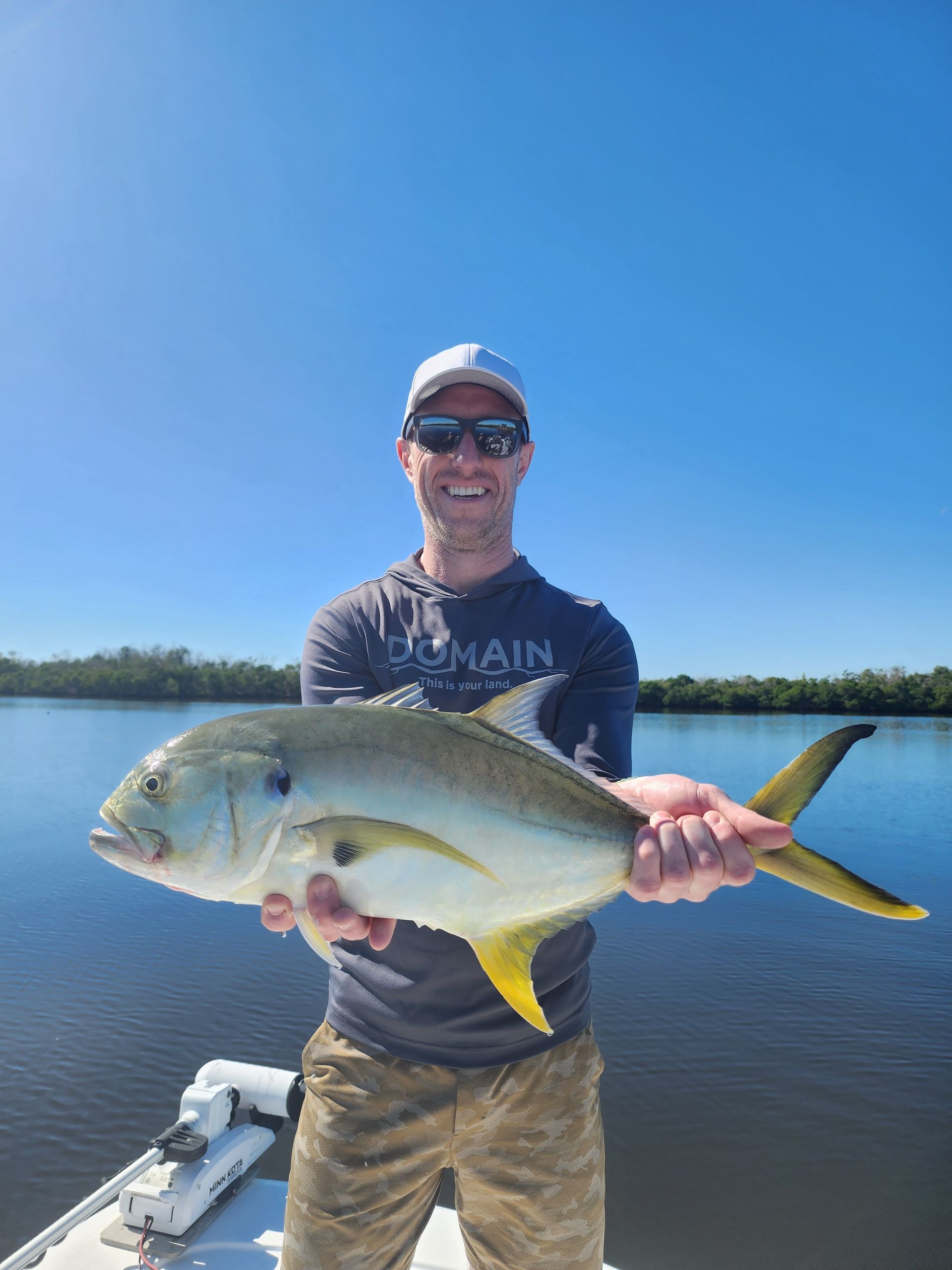A man is holding a large fish on a boat in the water.