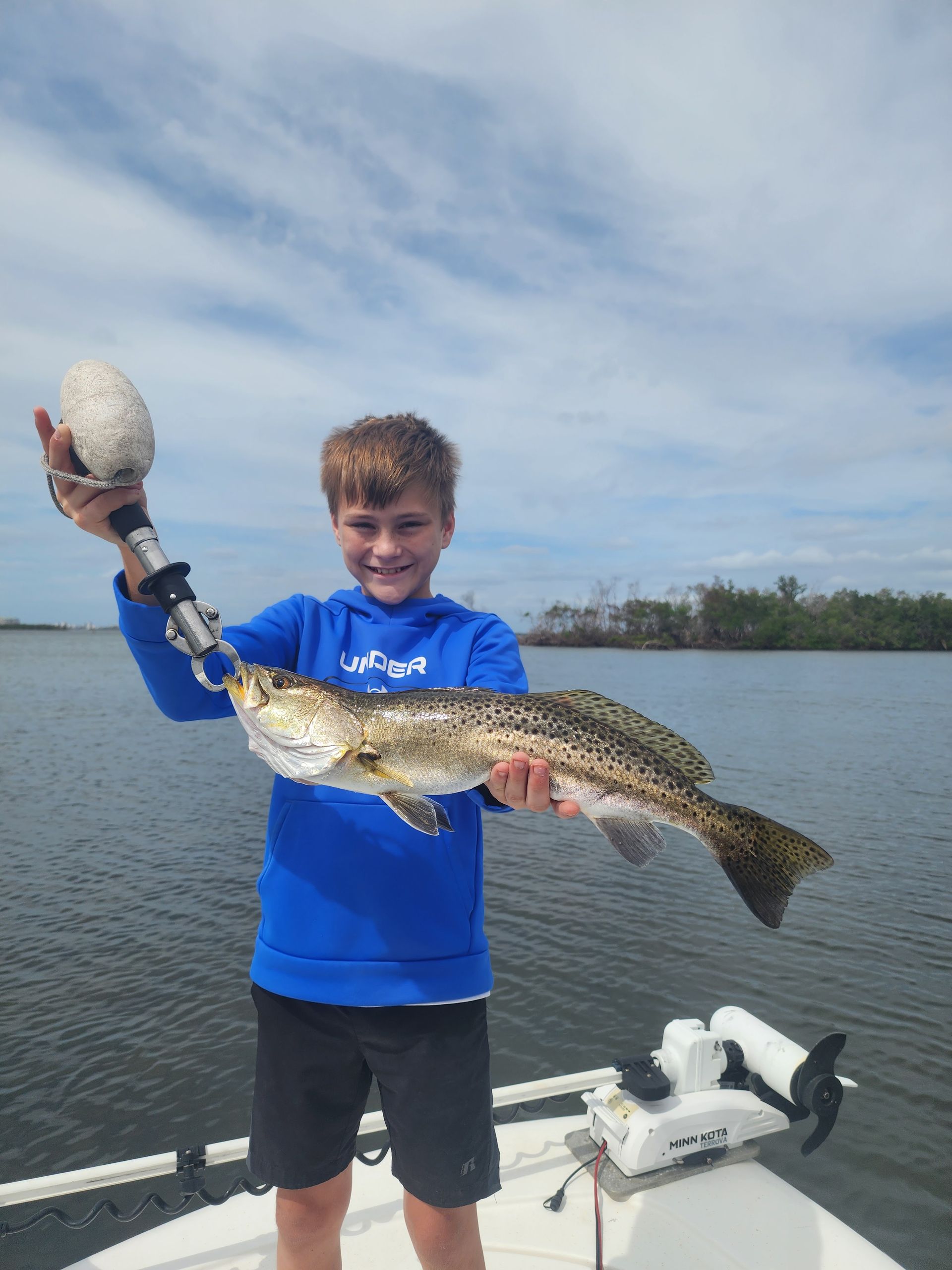 A young boy is holding a fish on a boat.