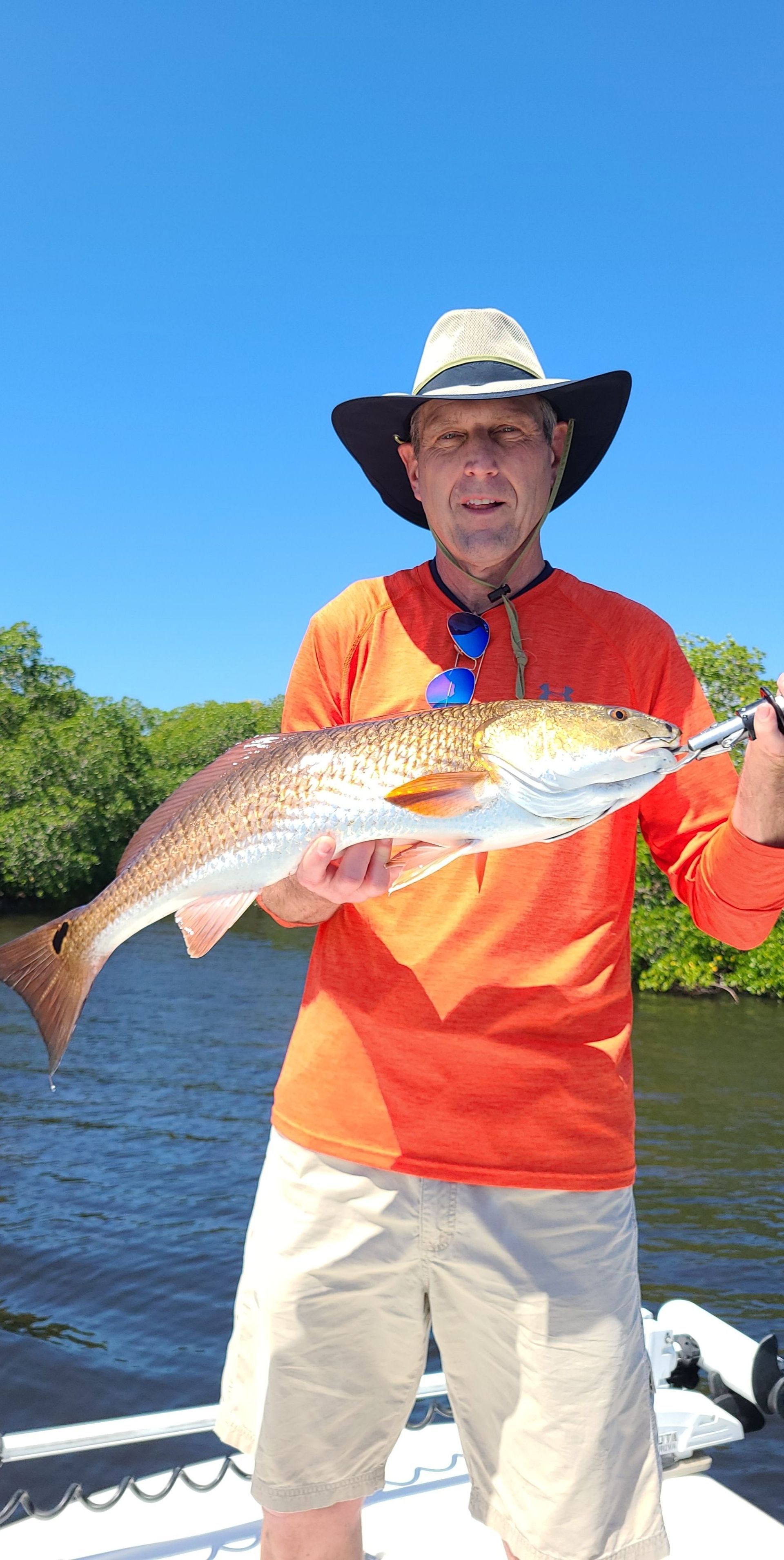 A man is holding a large red fish on a boat.