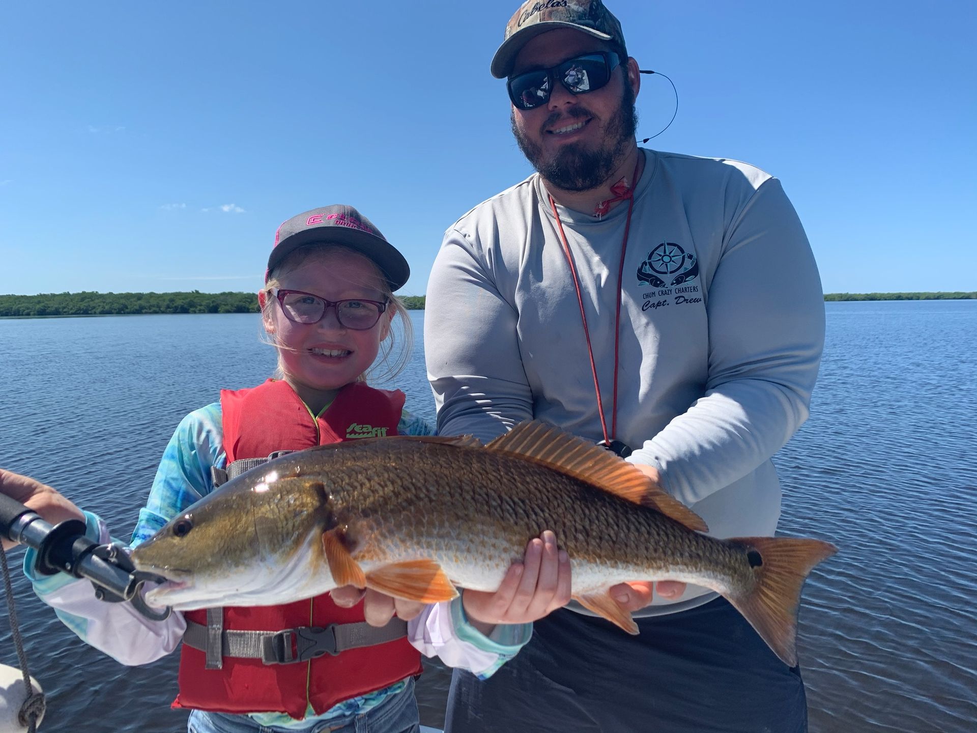 A man and a boy are holding a large fish in their hands.