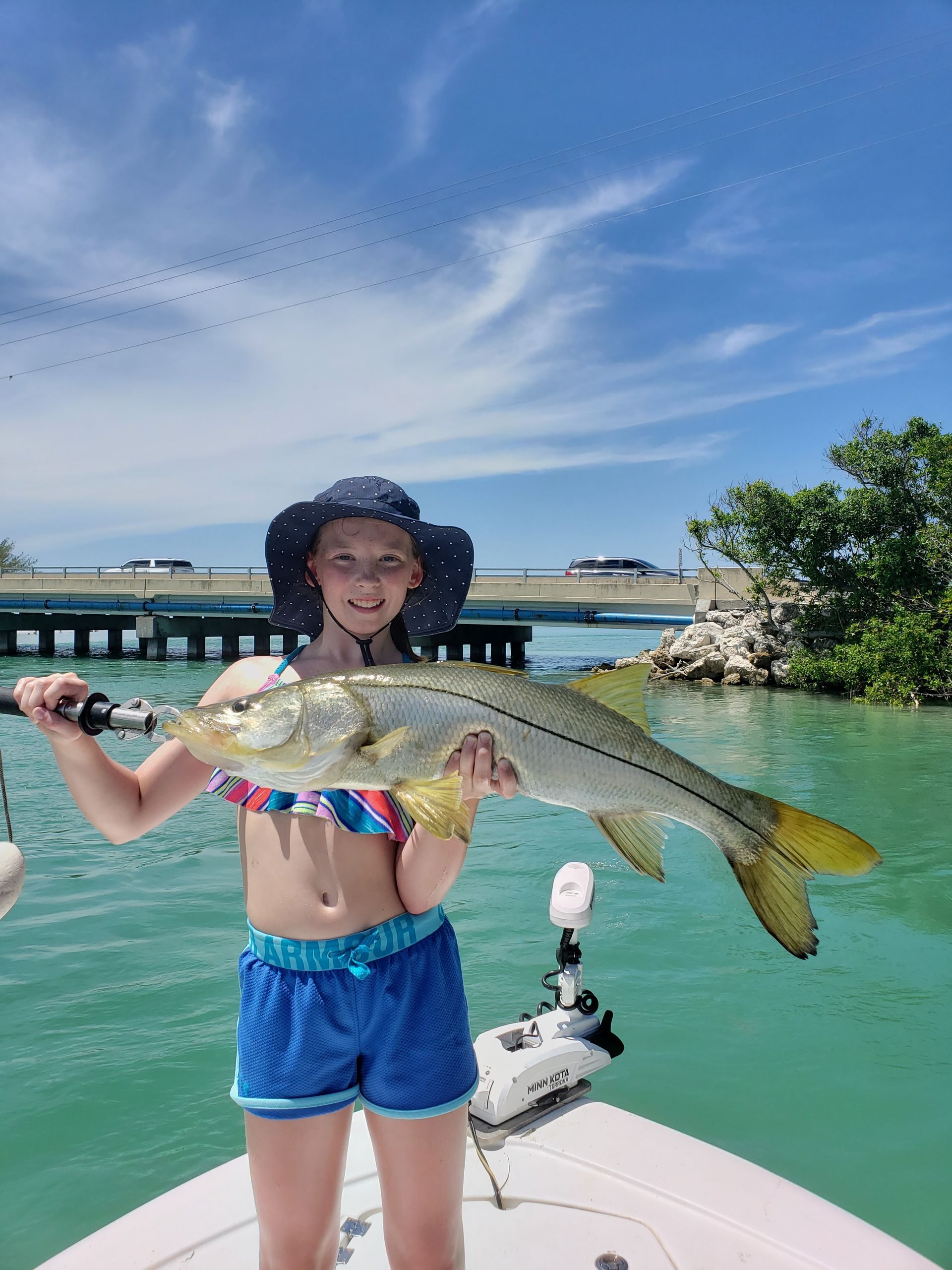A young girl is holding a large fish on a boat.
