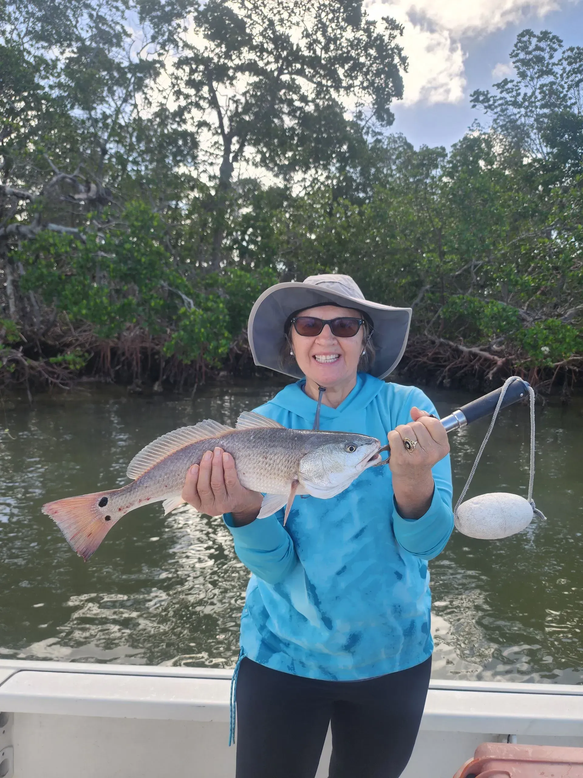 A woman is holding a large fish on a boat.