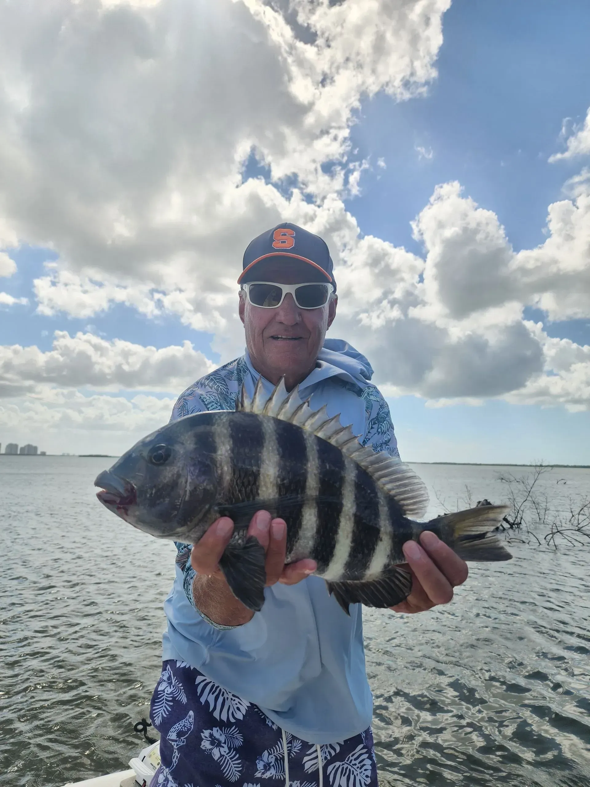 A man is holding a large fish in his hands in the water.