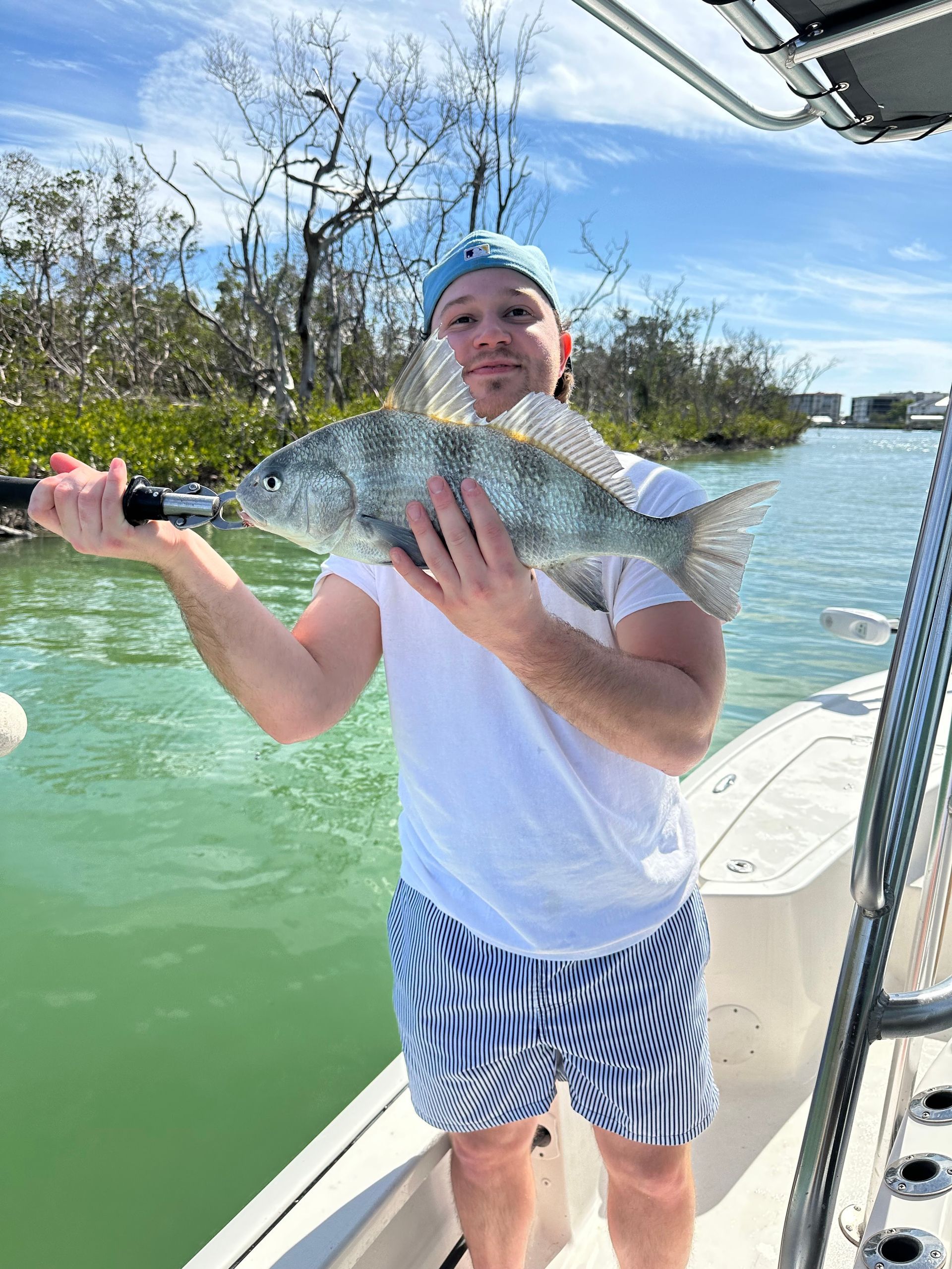 A man is standing on a boat holding a large fish.