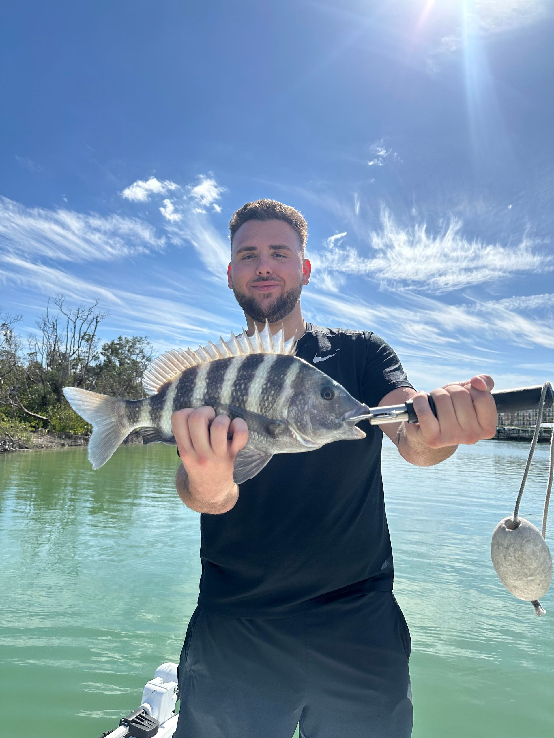 A man is holding a large fish in his hands on a boat.