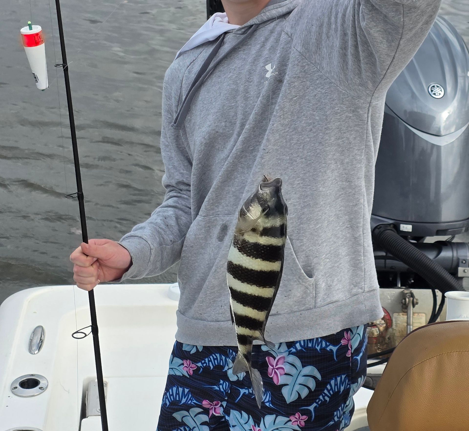A man on a boat holding a striped fish