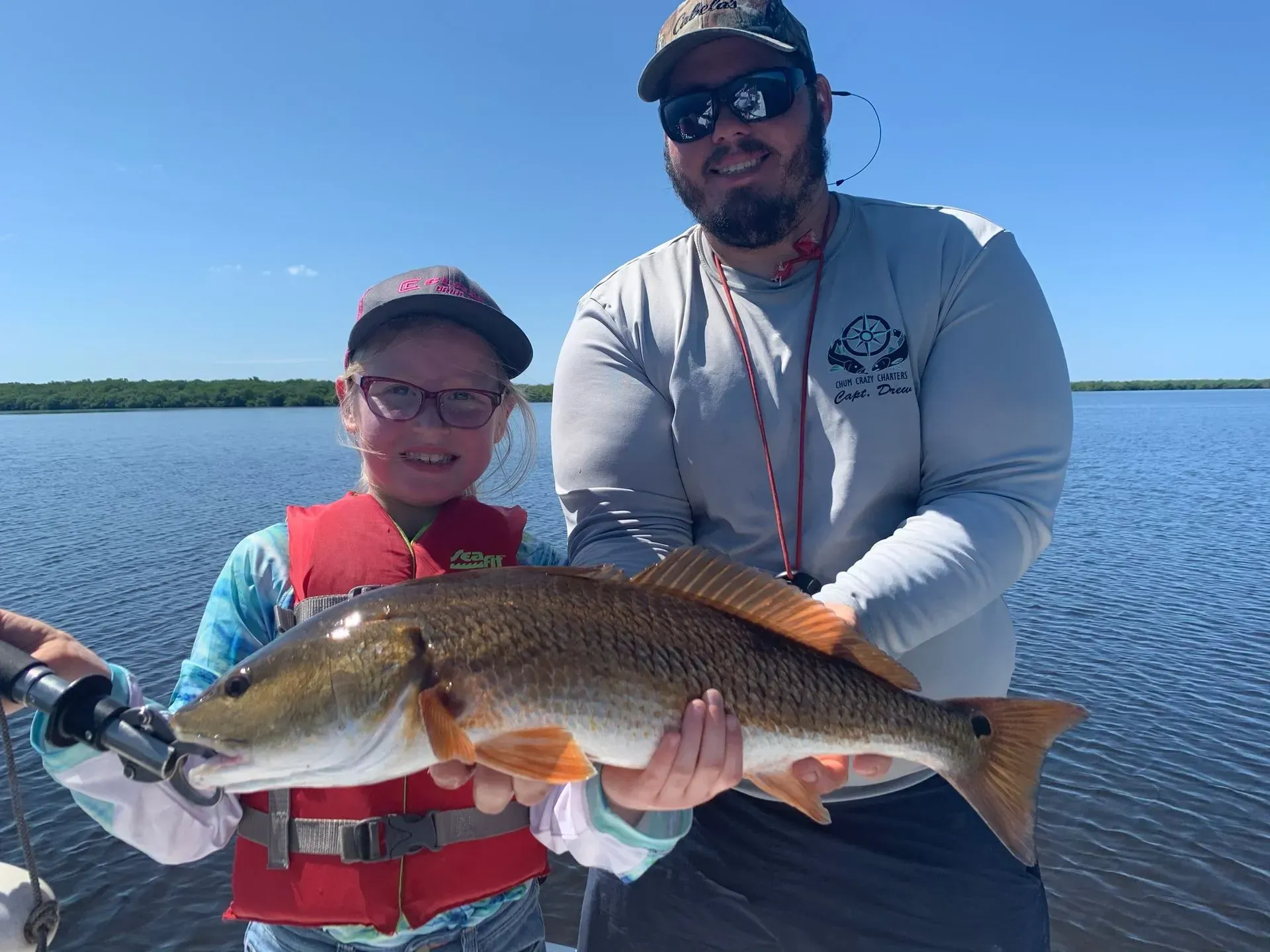 A man and a boy are holding a large fish on a boat.