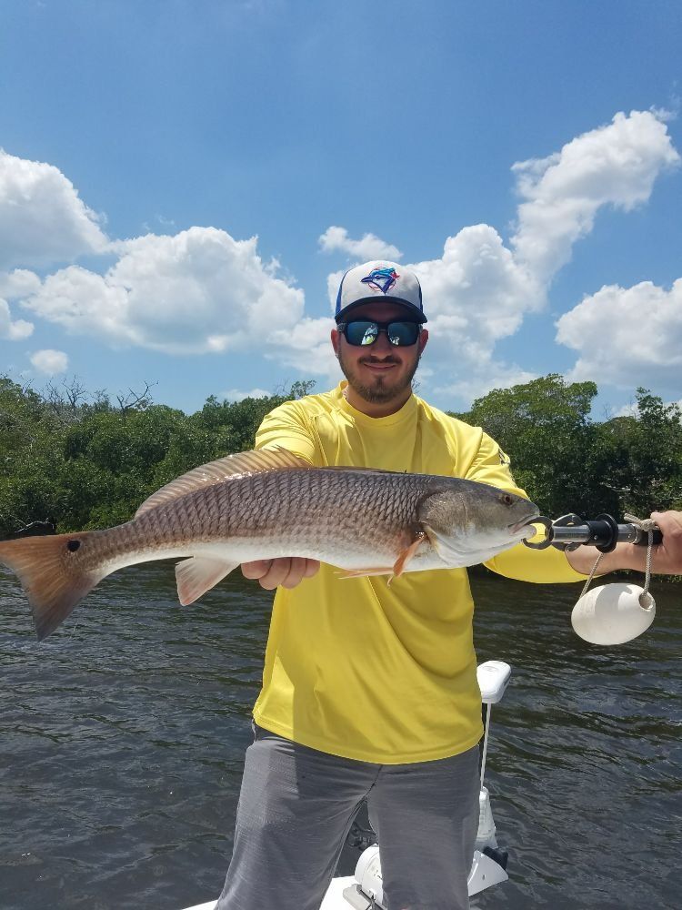 A man is holding a large redfish on a boat.