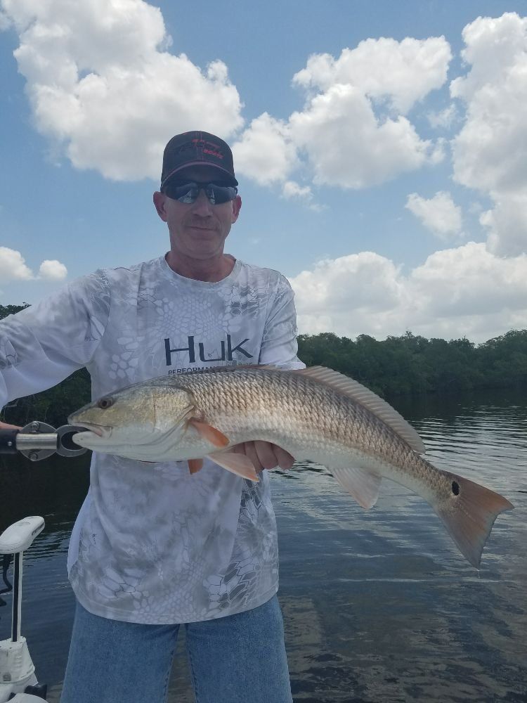A man is holding a large redfish in his hands on a boat.