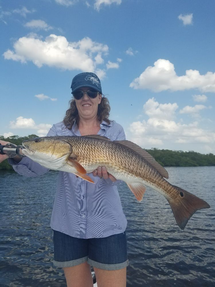 A woman is holding a large red fish in her hands in the water.