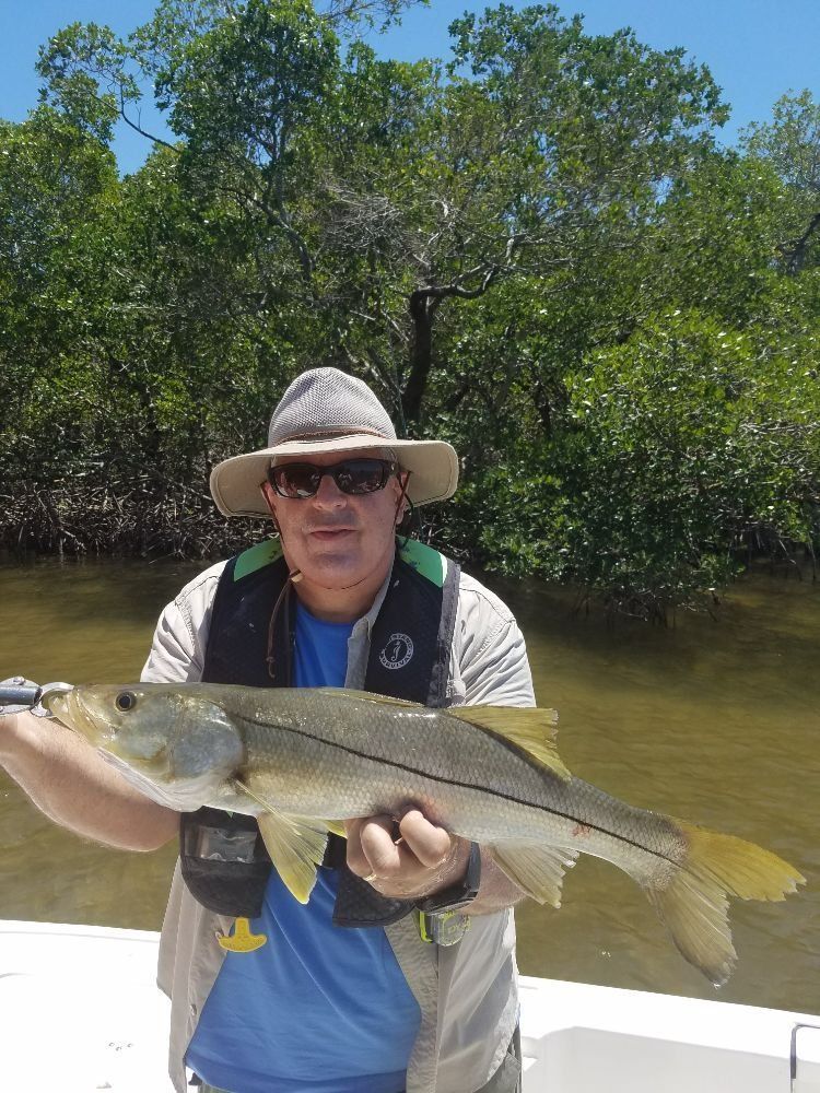 A man is holding a large fish in his hands on a boat.