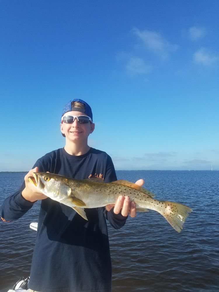 A young man is holding a fish in his hands in the water.