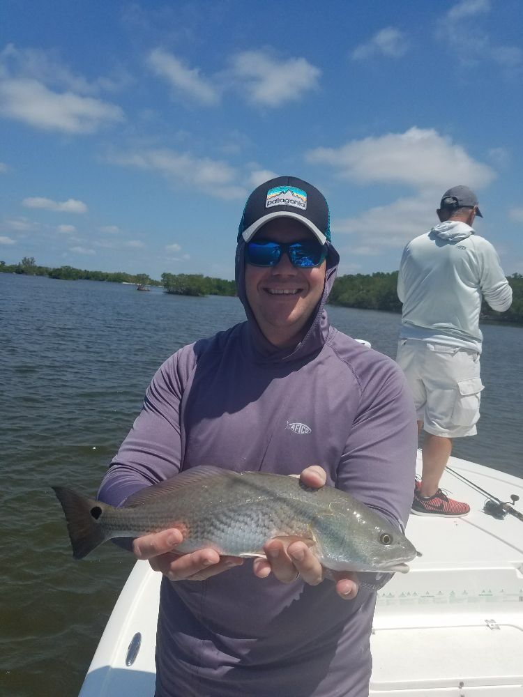 A man is holding a fish on a boat in the water.