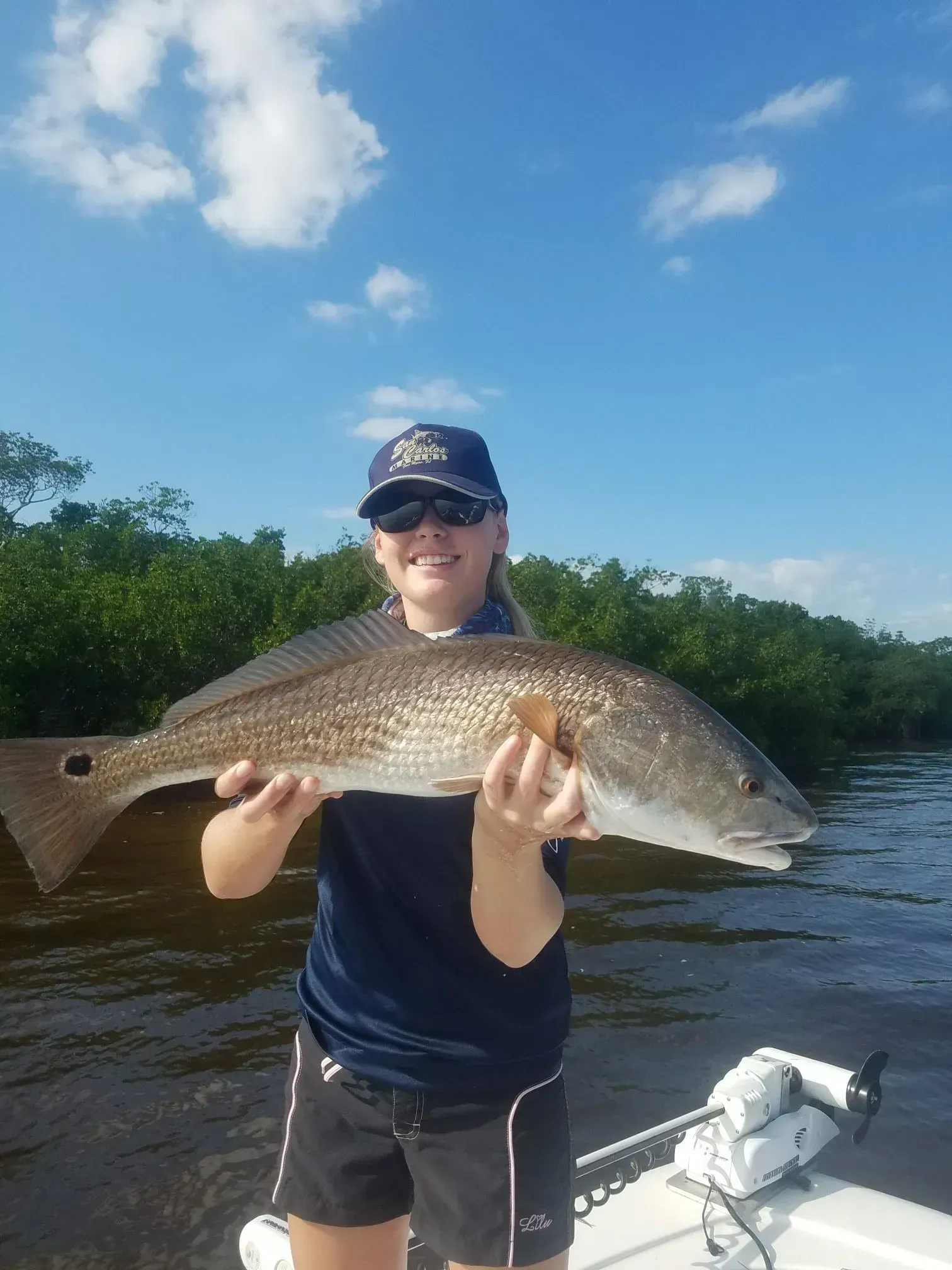 A woman is holding a large fish on a boat.