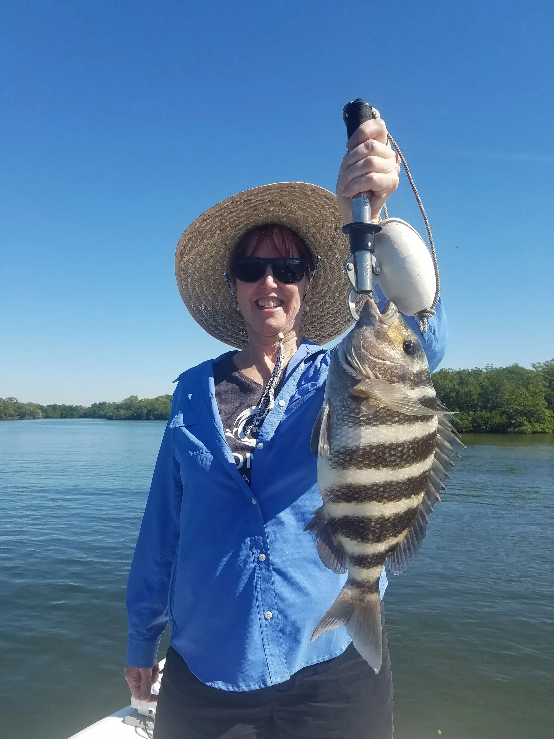 A woman is holding a fish on a boat in the water.