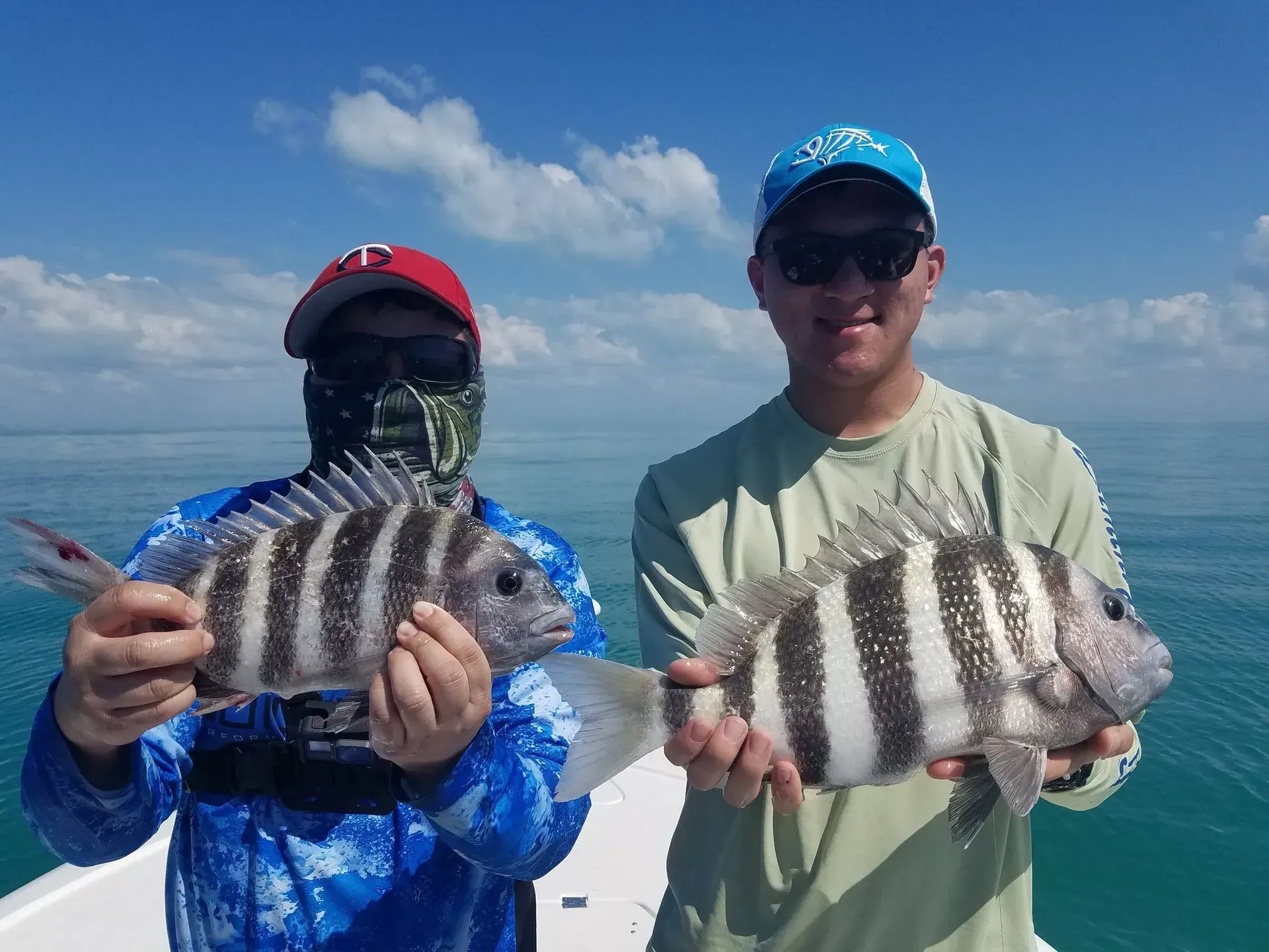 Two men are holding fish on a boat in the ocean.