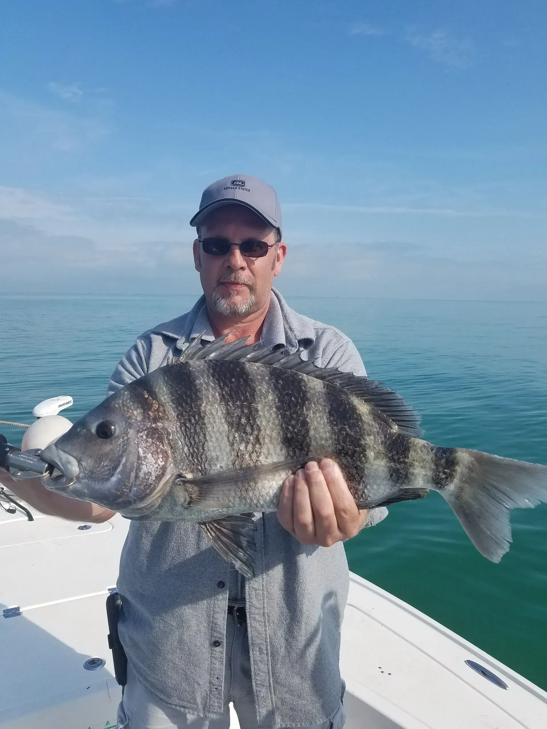 A man is holding a large fish on a boat.